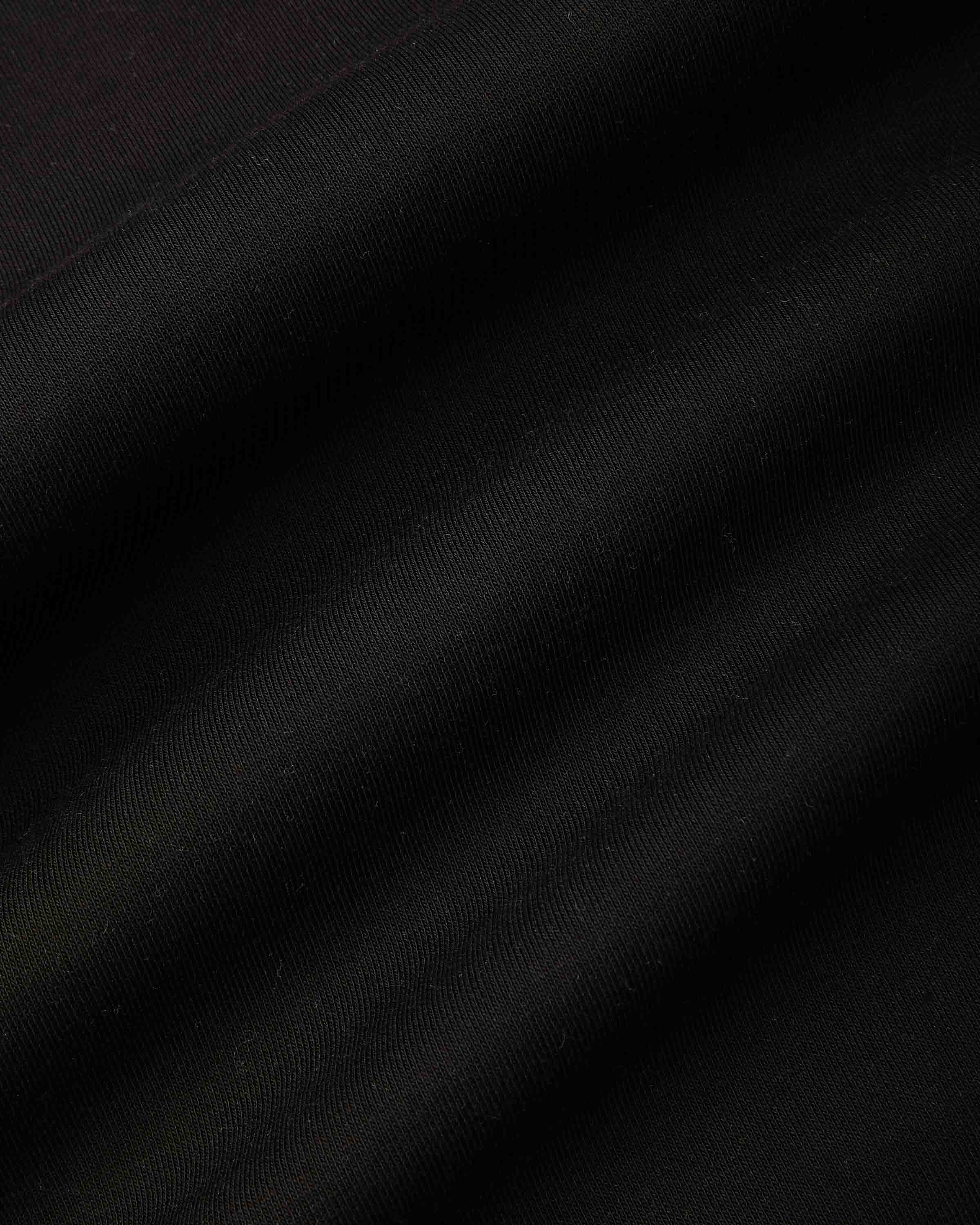 A close-up of a black fabric texture with soft diagonal folds and a subtle sheen.