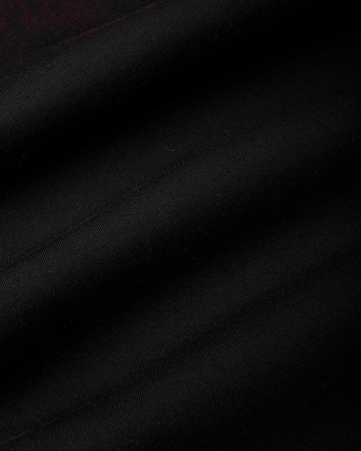 A close-up of black fabric with soft diagonal folds and a subtle woven texture.
