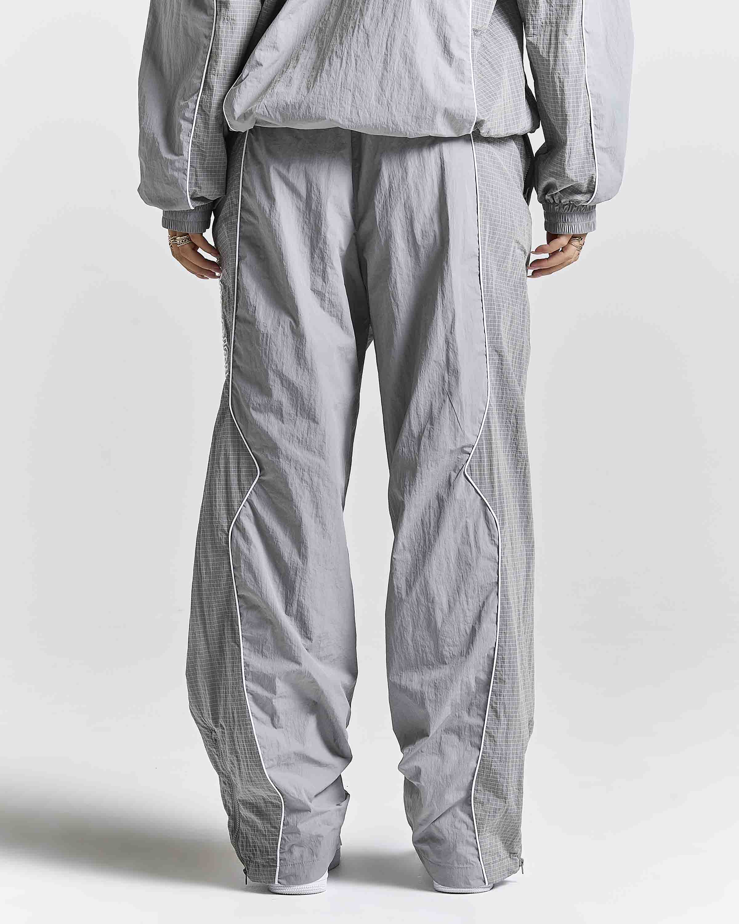 A person shown from the back wearing loose, wide-leg gray textured pants and a matching gray top against a plain light gray studio background.