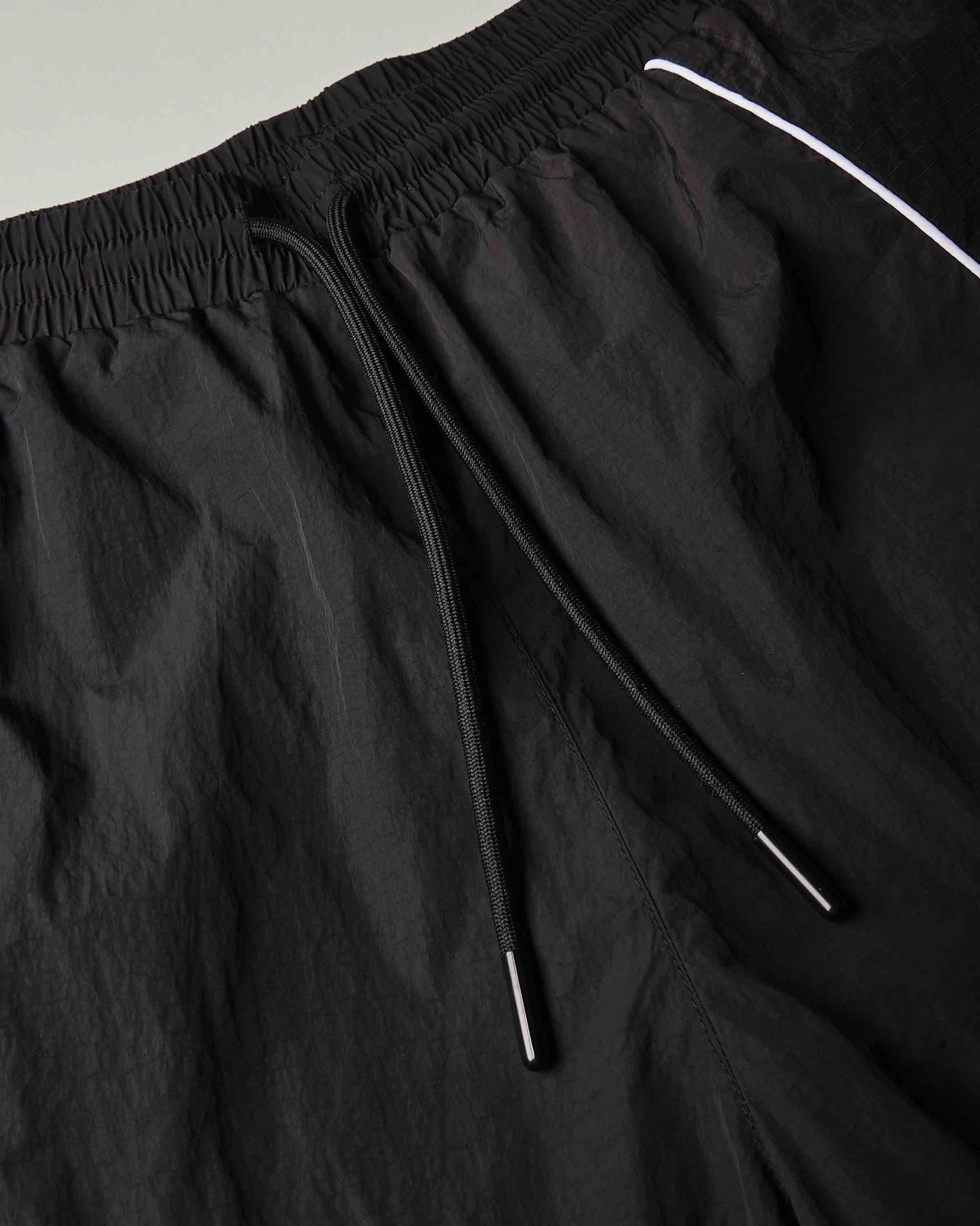 Close-up of black drawstring shorts with a white piping accent near the waistband.