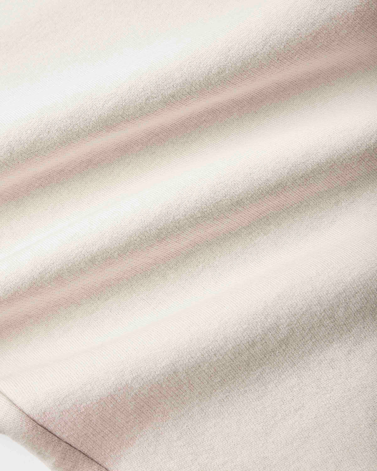 A close-up of a soft, textured fabric with a fine knit pattern, featuring horizontal stripes in cream, light beige, and a muted dusty pink.