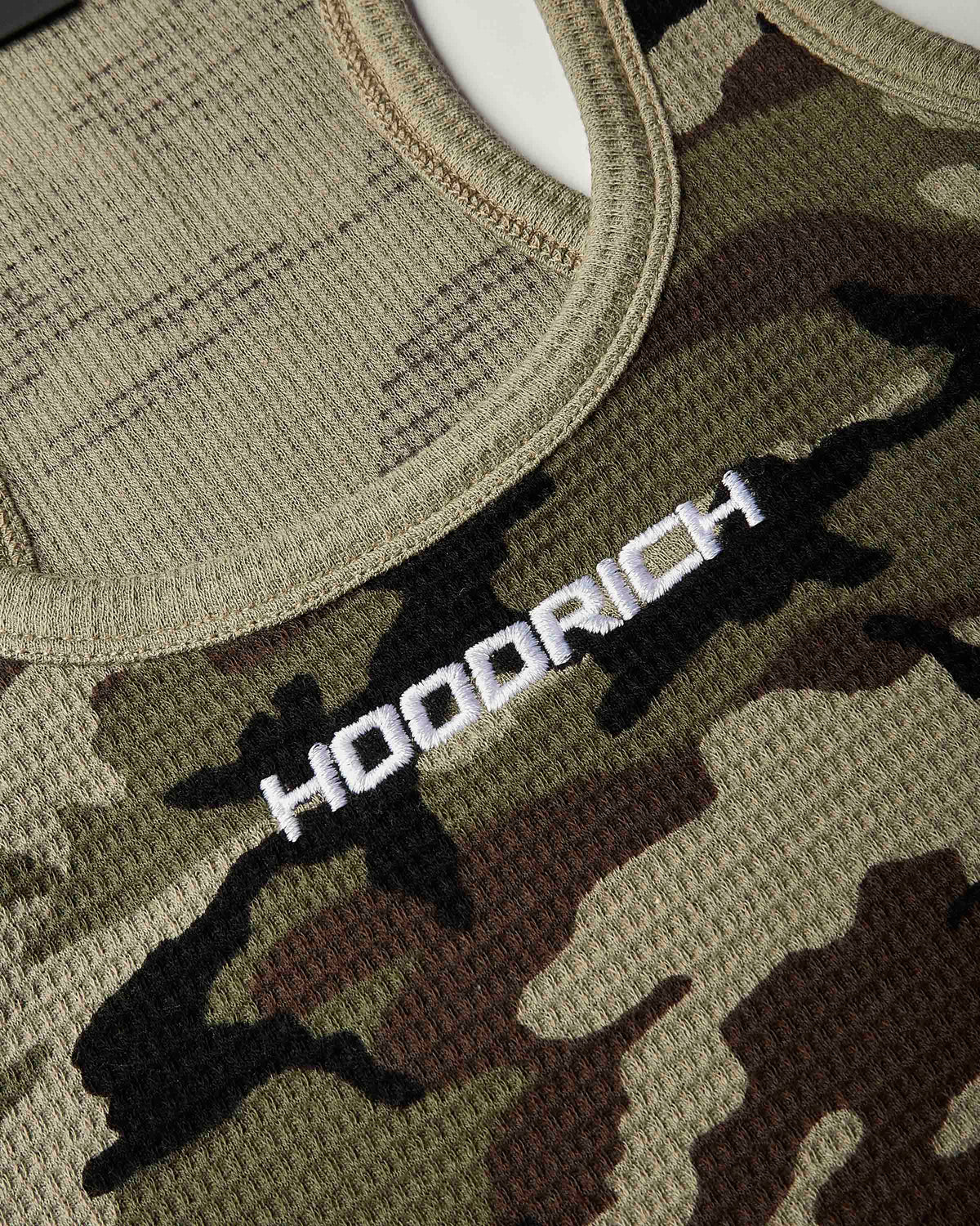 Close-up of a camouflage knit top with a white embroidered 'HOODRICH' logo across the chest.