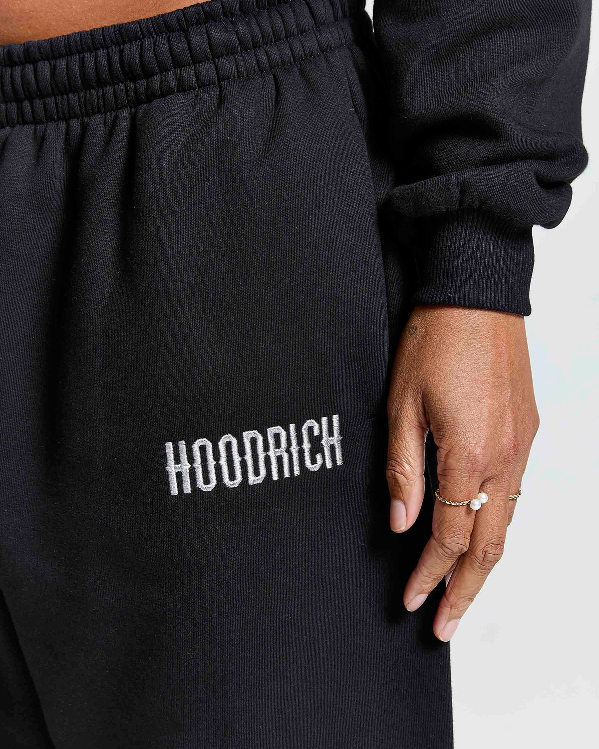 Displays a model wearing the Black 'Hoodrich' branded women's Solace Full Tracksuit featuring the hoodrich branding