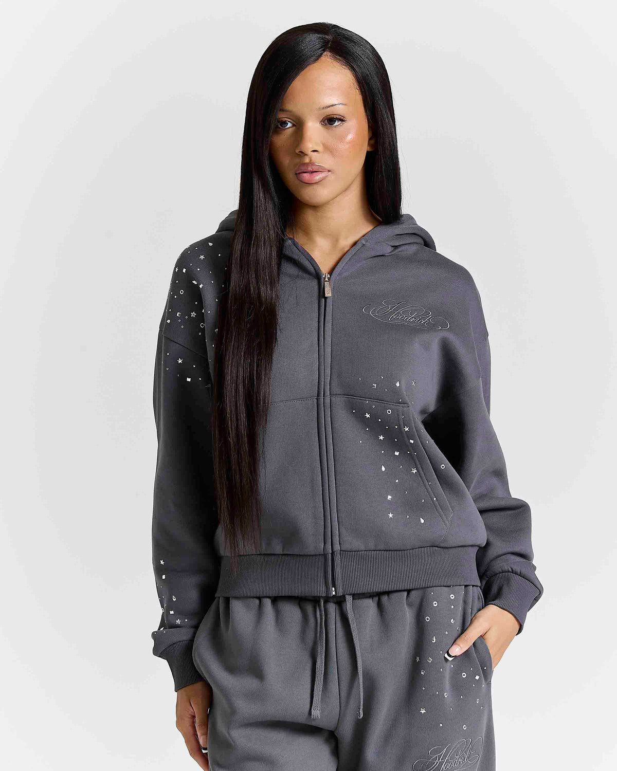 Displays a model wearing the Silver rhinestone 'Hoodrich' branded Clash V2 Mid Length Z/T Hoodie