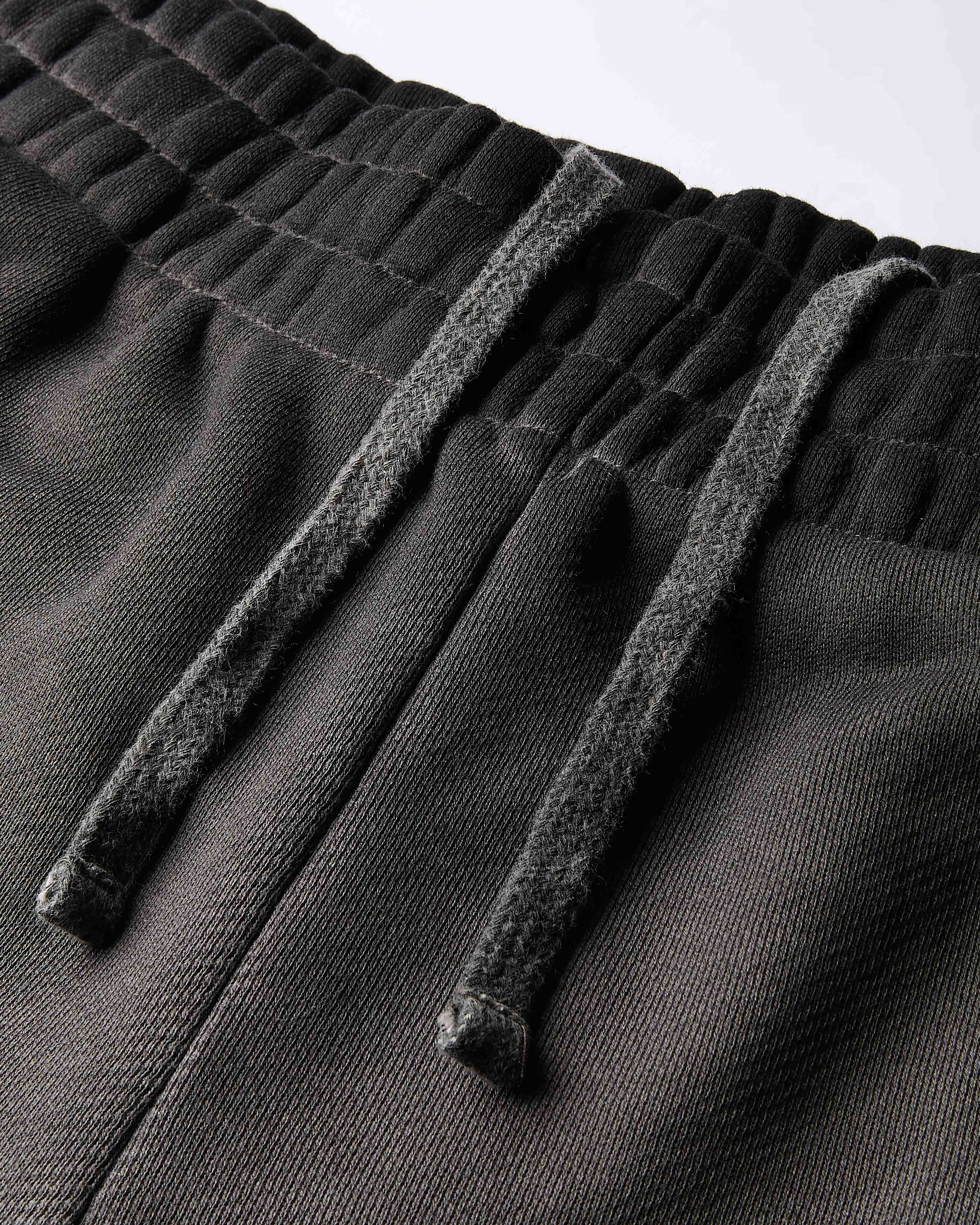 Close-up of the elasticated waistband and drawstring on the black oil wash shorts.