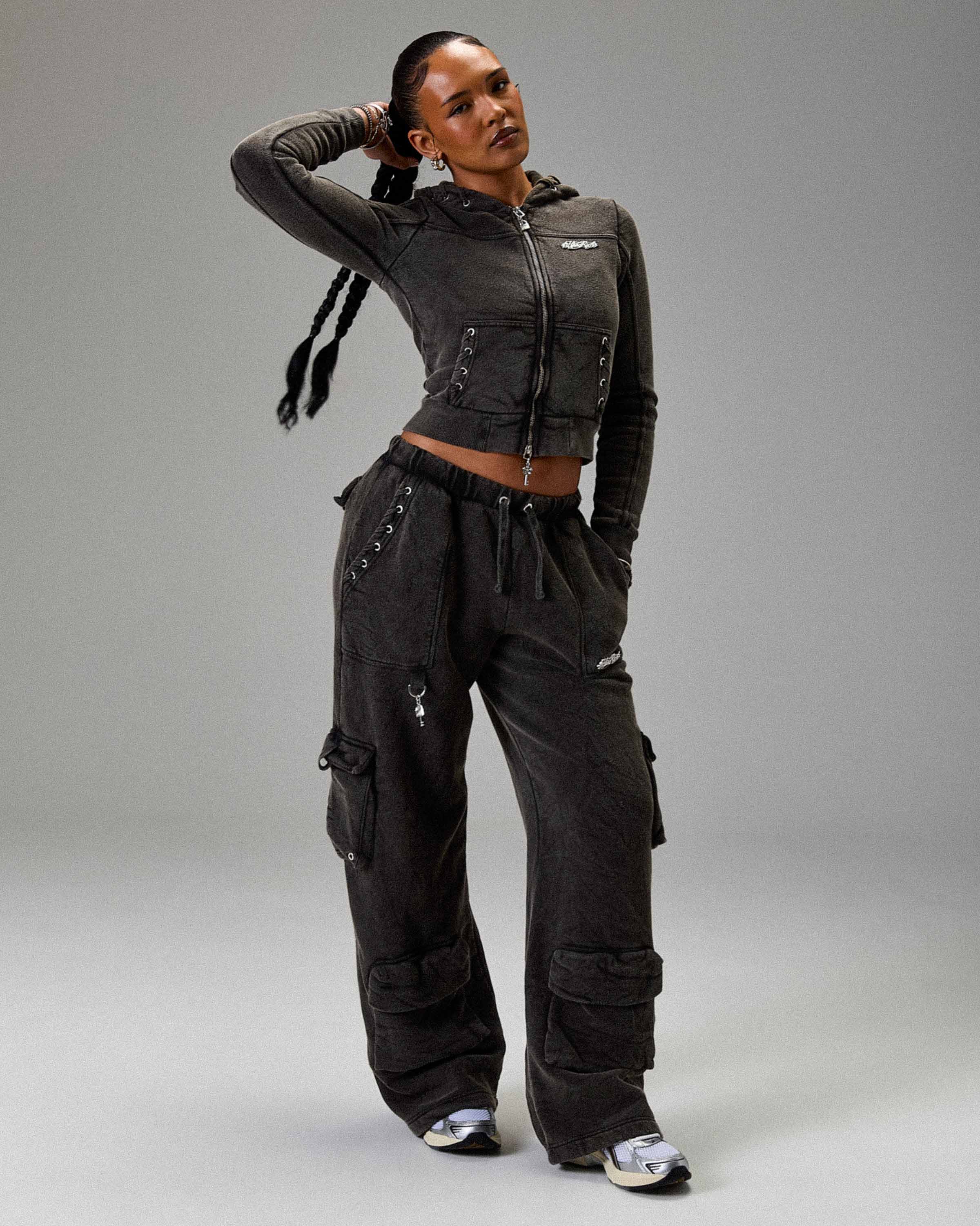 Person wearing a dark gray hoodie and cargo pants on a gray background