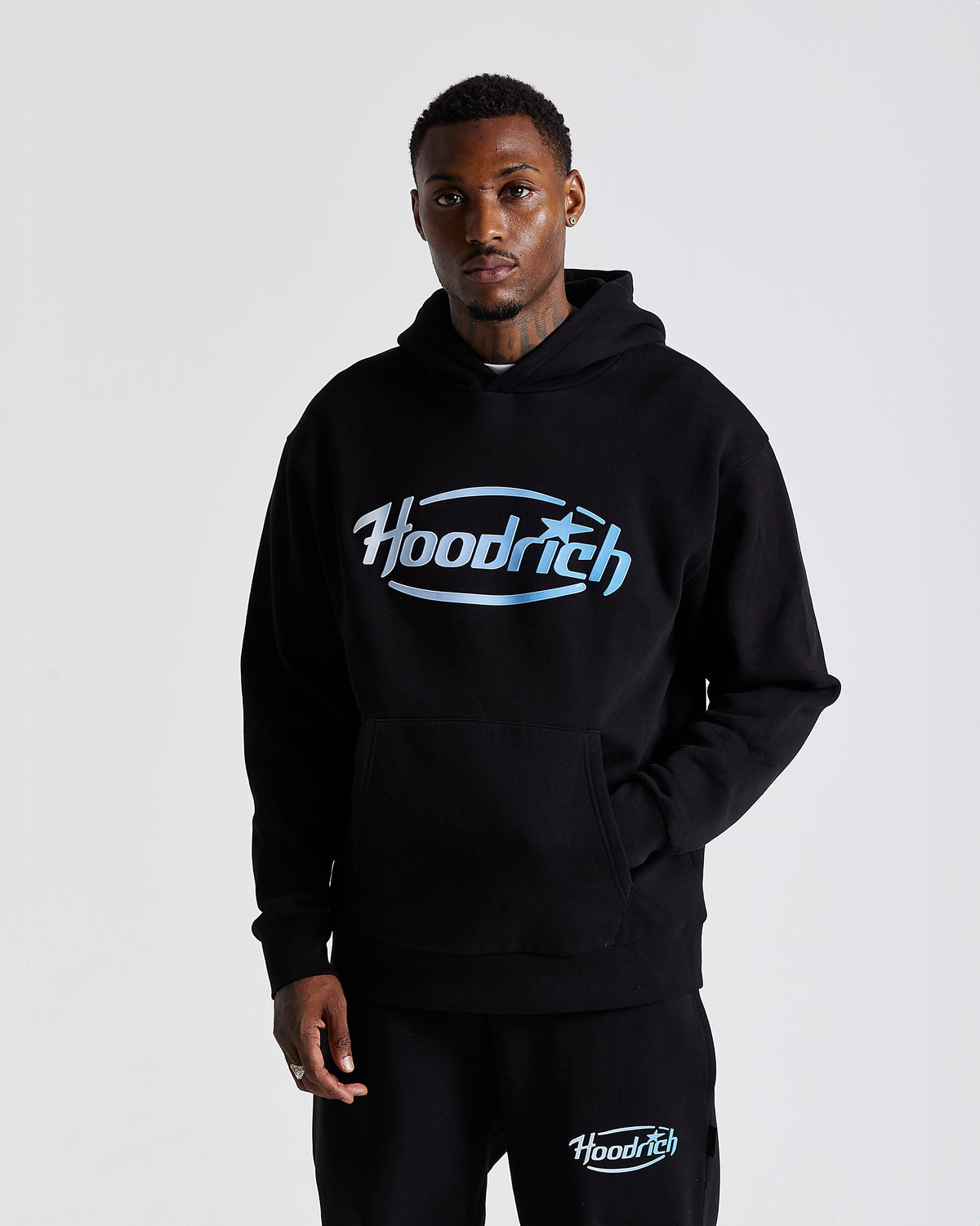 Displays a model wearing the Black 'Hoodrich' branded men's Curve Full Tracksuit