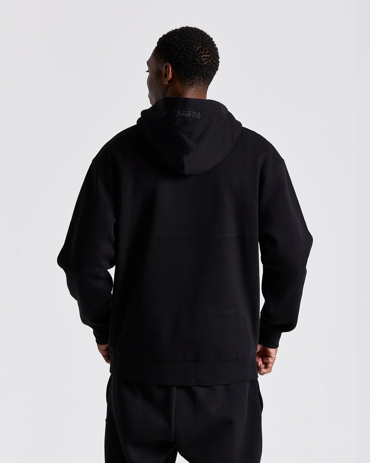 Displays a model wearing the Black 'Hoodrich' branded men's Curve Full Tracksuit