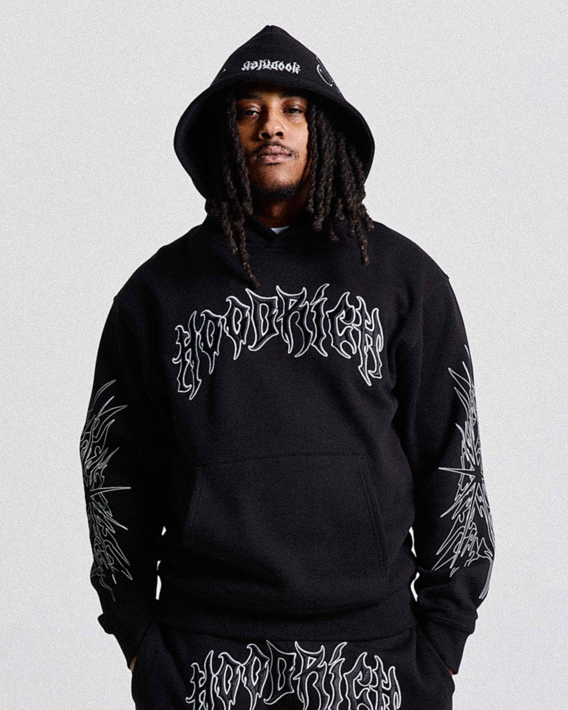 Person wearing a black hoodie with white text and designs on a light gray background