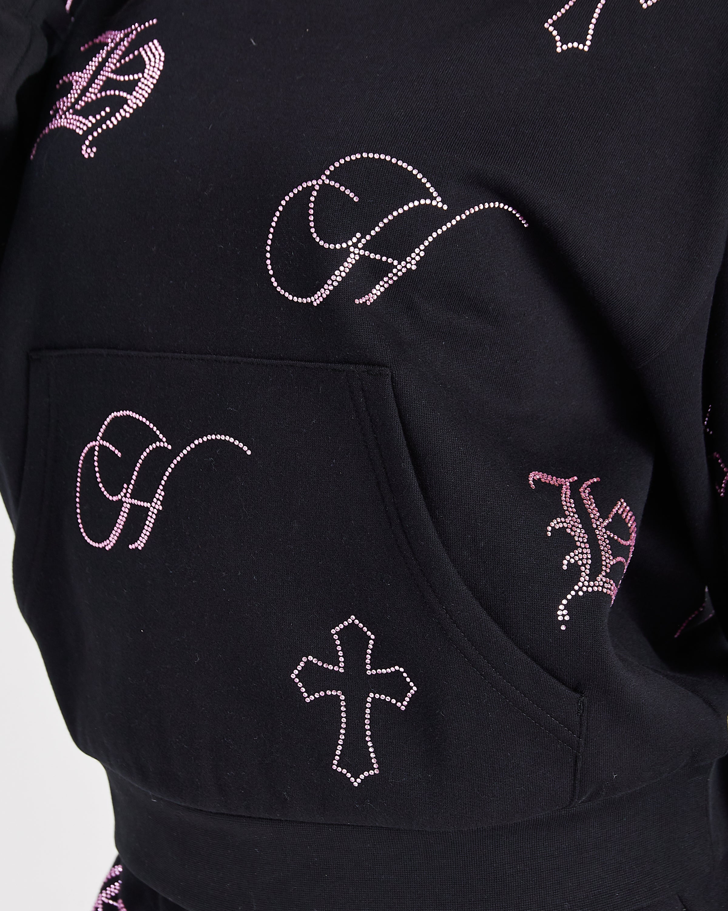 Close-up of a black hoodie featuring rhinestone-embellished gothic letter 'H' and cross motifs, with a front kangaroo pocket.