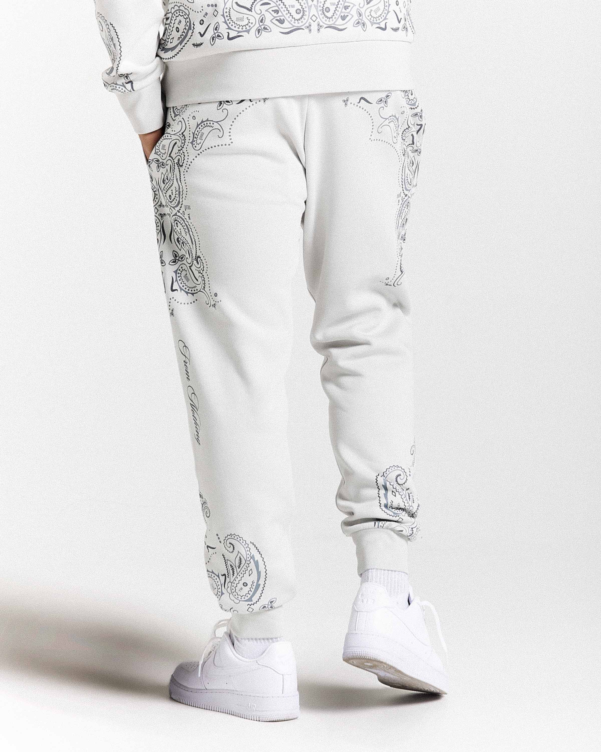 White pants with intricate silver patterns worn by a person on a white background