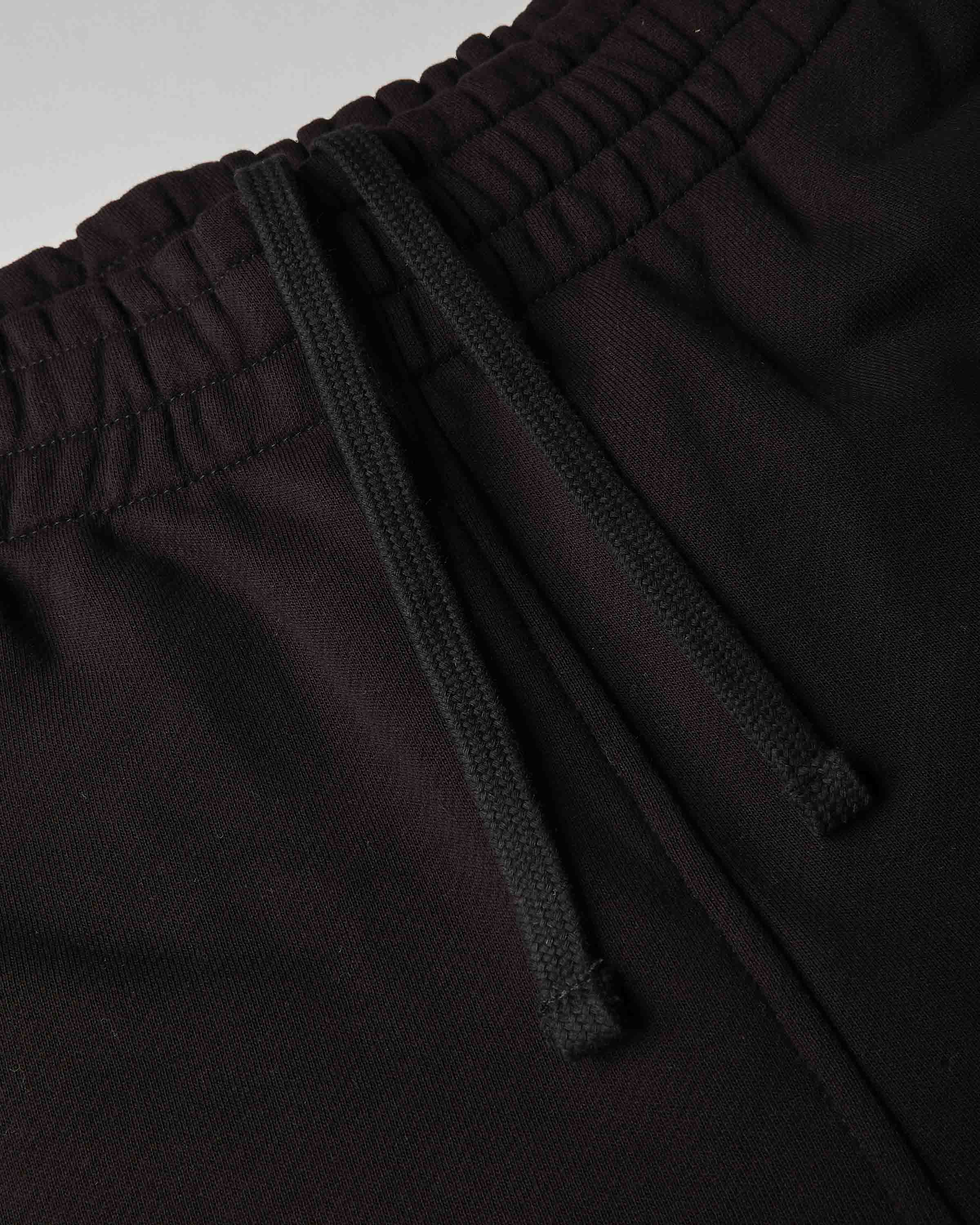 Close-up of dark burgundy or very deep wine pants with a black drawstring waistband, showing the fabric texture and elasticized waist.