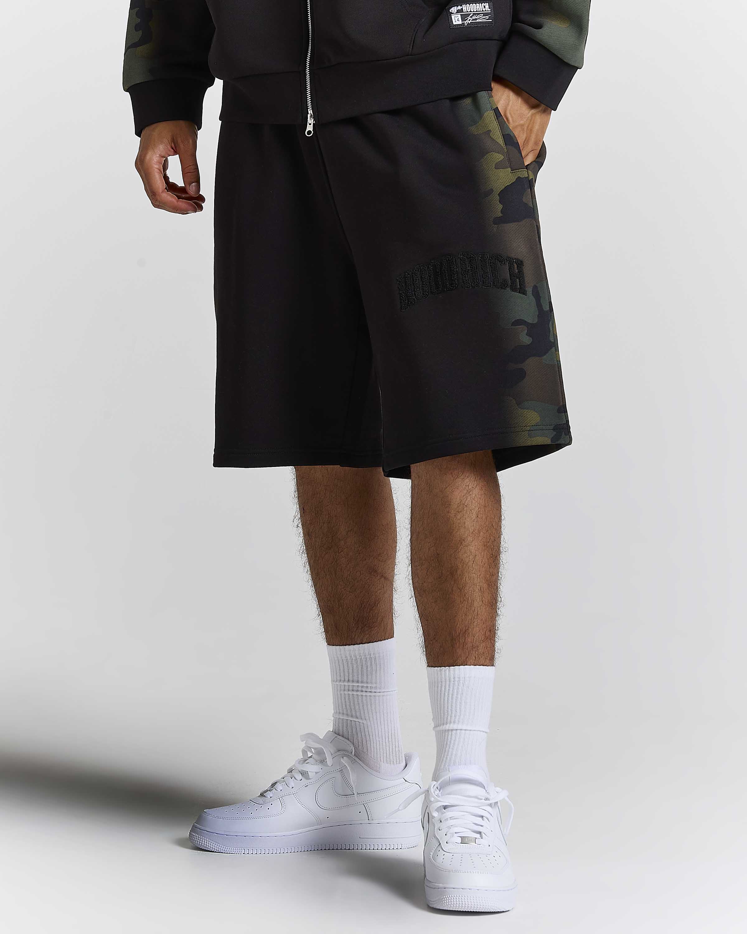 Displays a model wearing the Black Camo 'Hoodrich' branded men's Shade Matching Shorts Set 