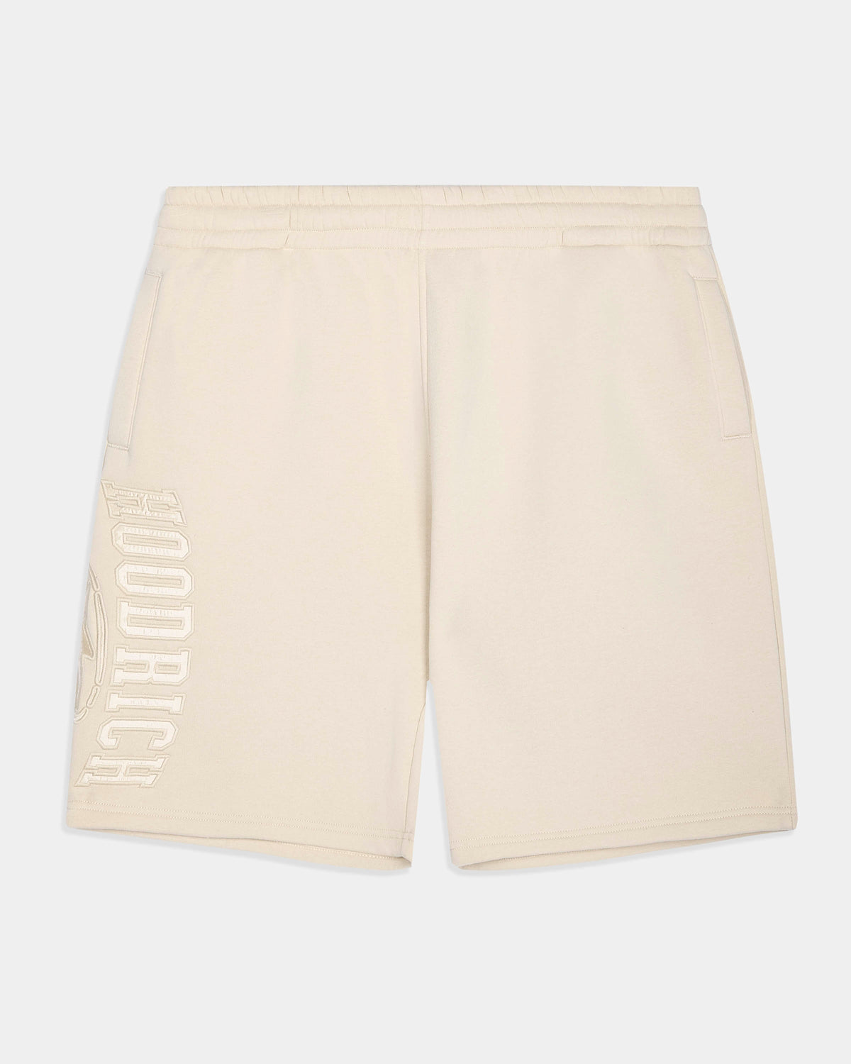 Cream-colored athletic shorts with a vertical 'HOODRICH' logo printed in tonal cream on the left leg, shown against a light gray background.