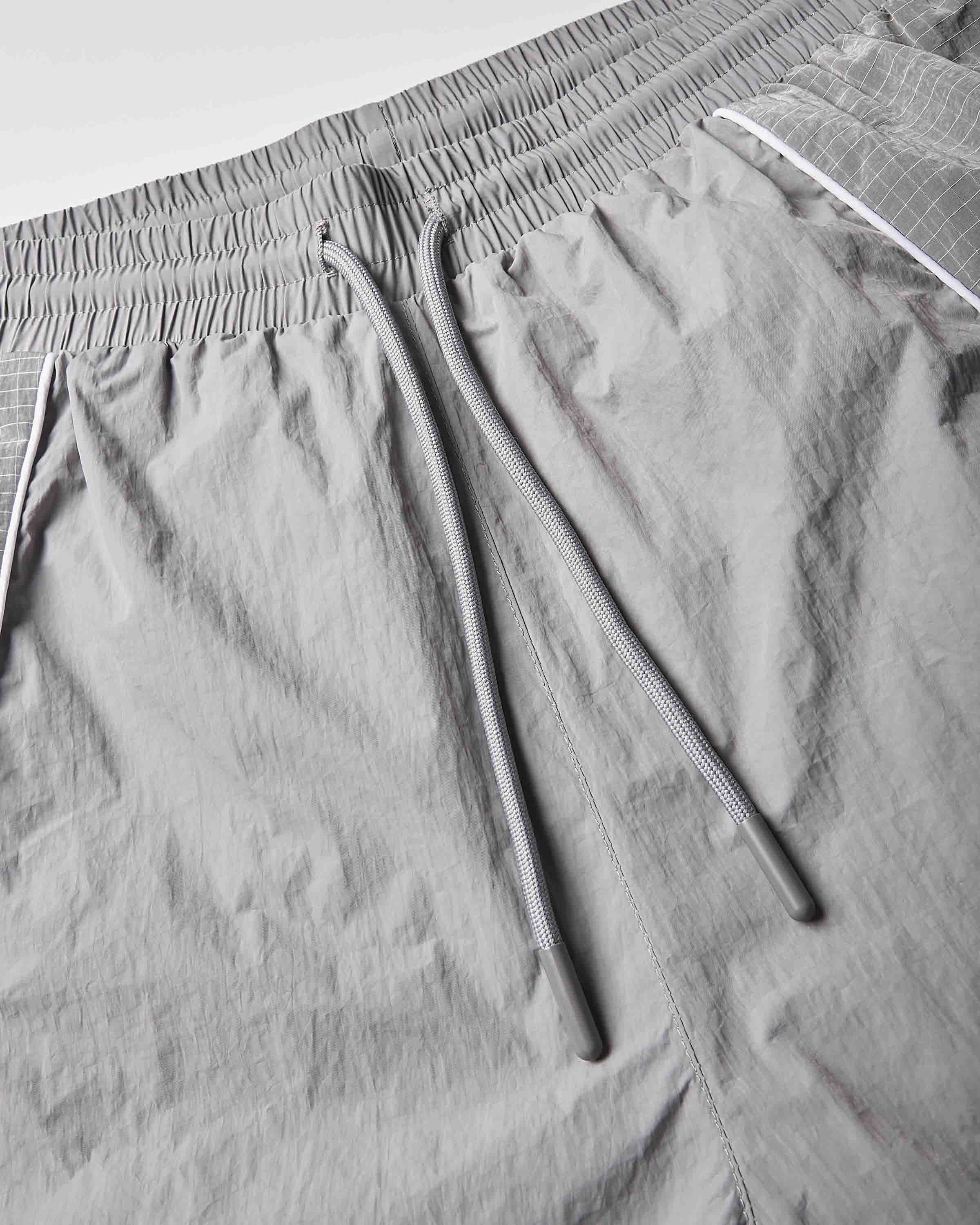 Close-up of light gray athletic shorts showing the elastic waistband, drawstring, and textured fabric.