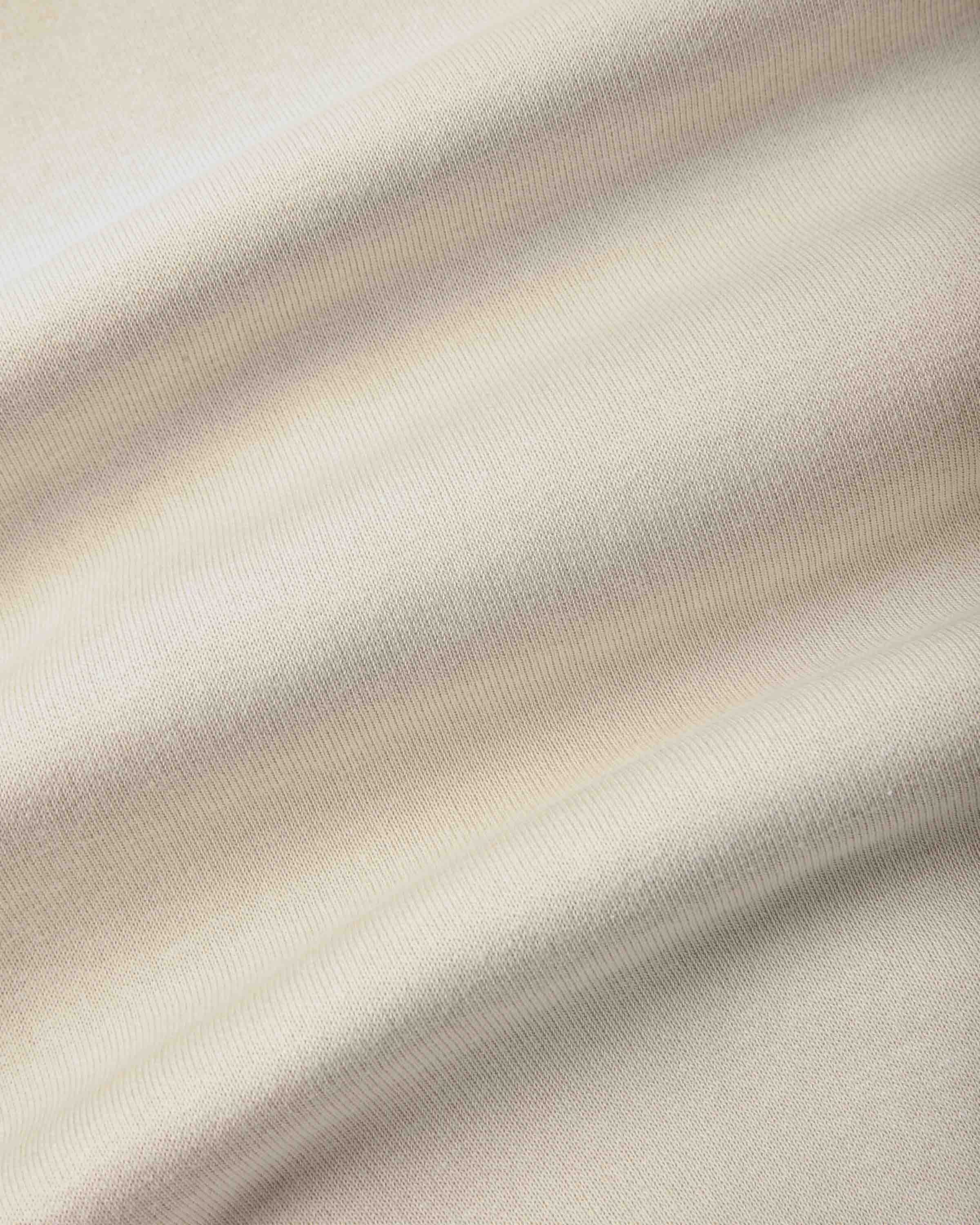 A close-up of draped fabric with a soft, warm off-white or cream tone and subtle pinkish-beige shading from the folds.