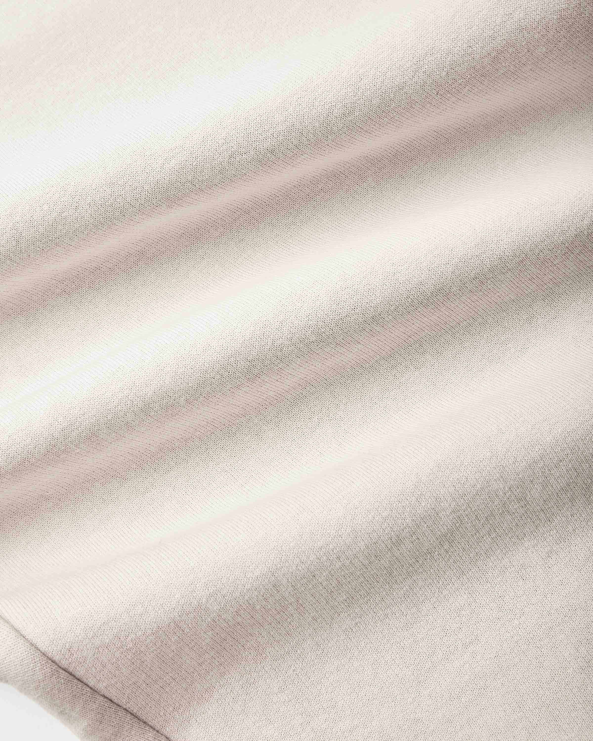 A close-up of a soft, textured fabric with a fine knit pattern, featuring horizontal stripes in cream, light beige, and a muted dusty pink.