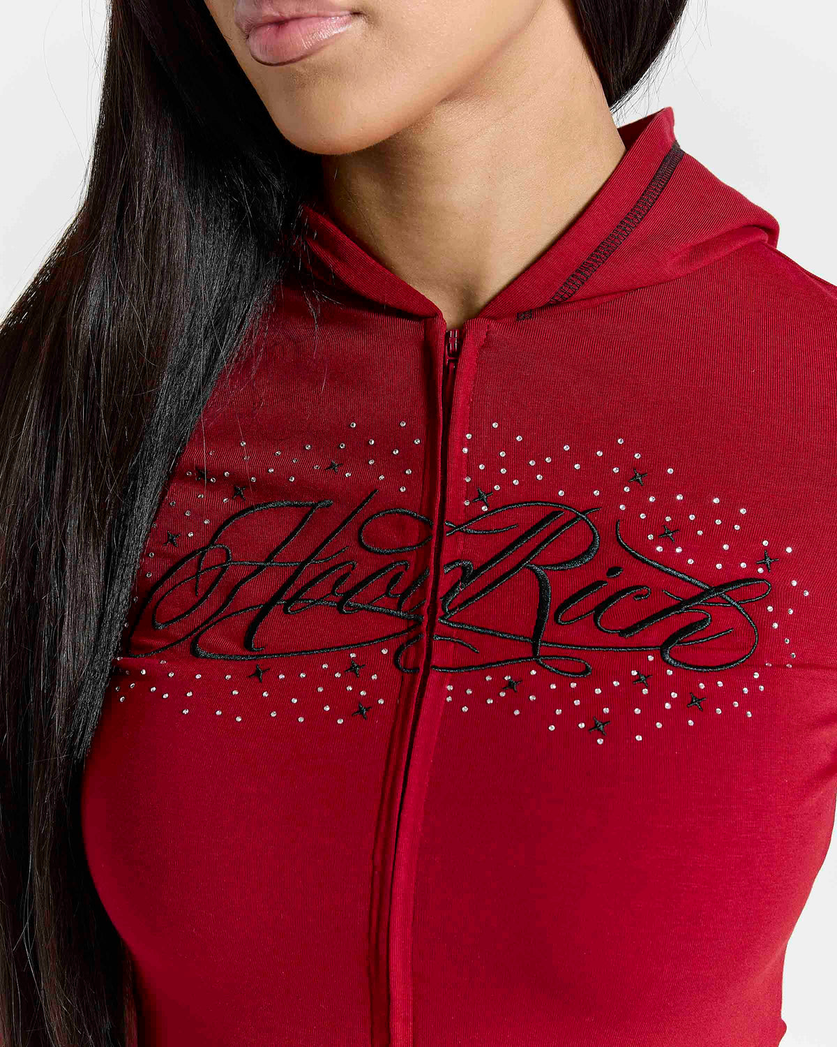 Displays a model wearing the Red 'Hoodrich' branded women's Gleam Full Tracksuit featuring the details on the branding 