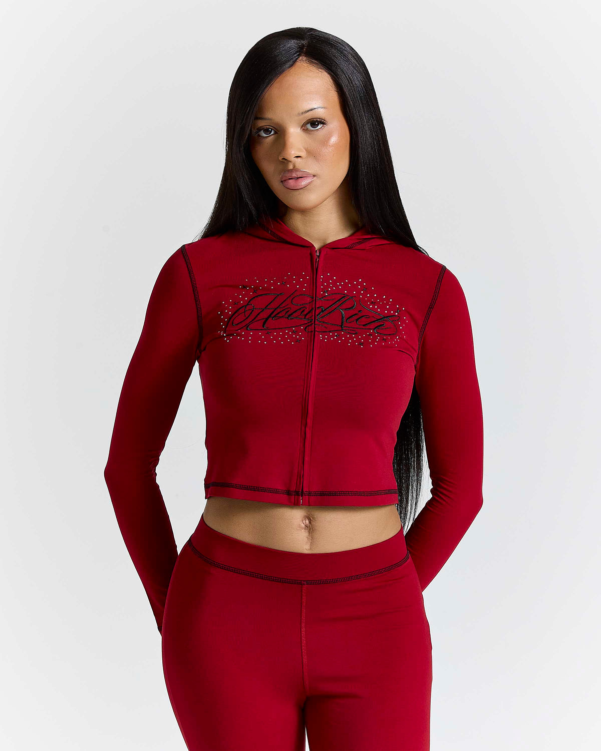 Displays a model wearing the Red 'Hoodrich' branded women's Gleam Full Tracksuit