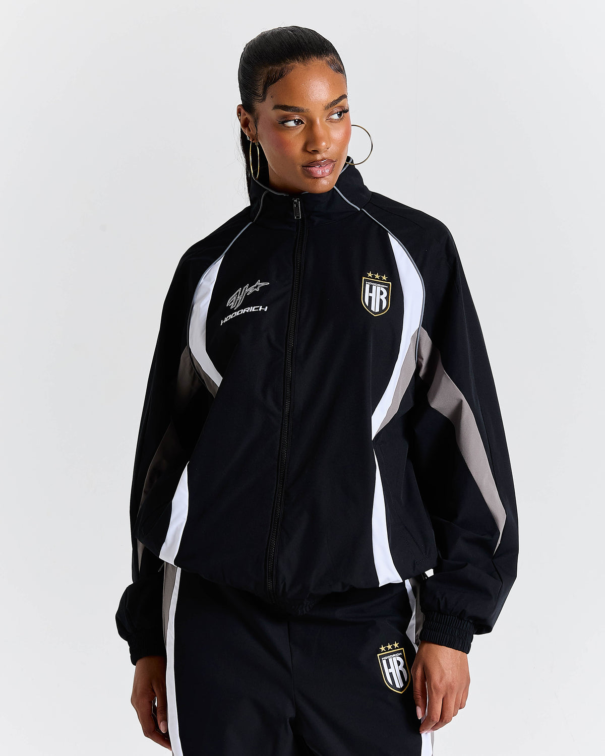 Person wearing a black tracksuit with white accents on a light gray background