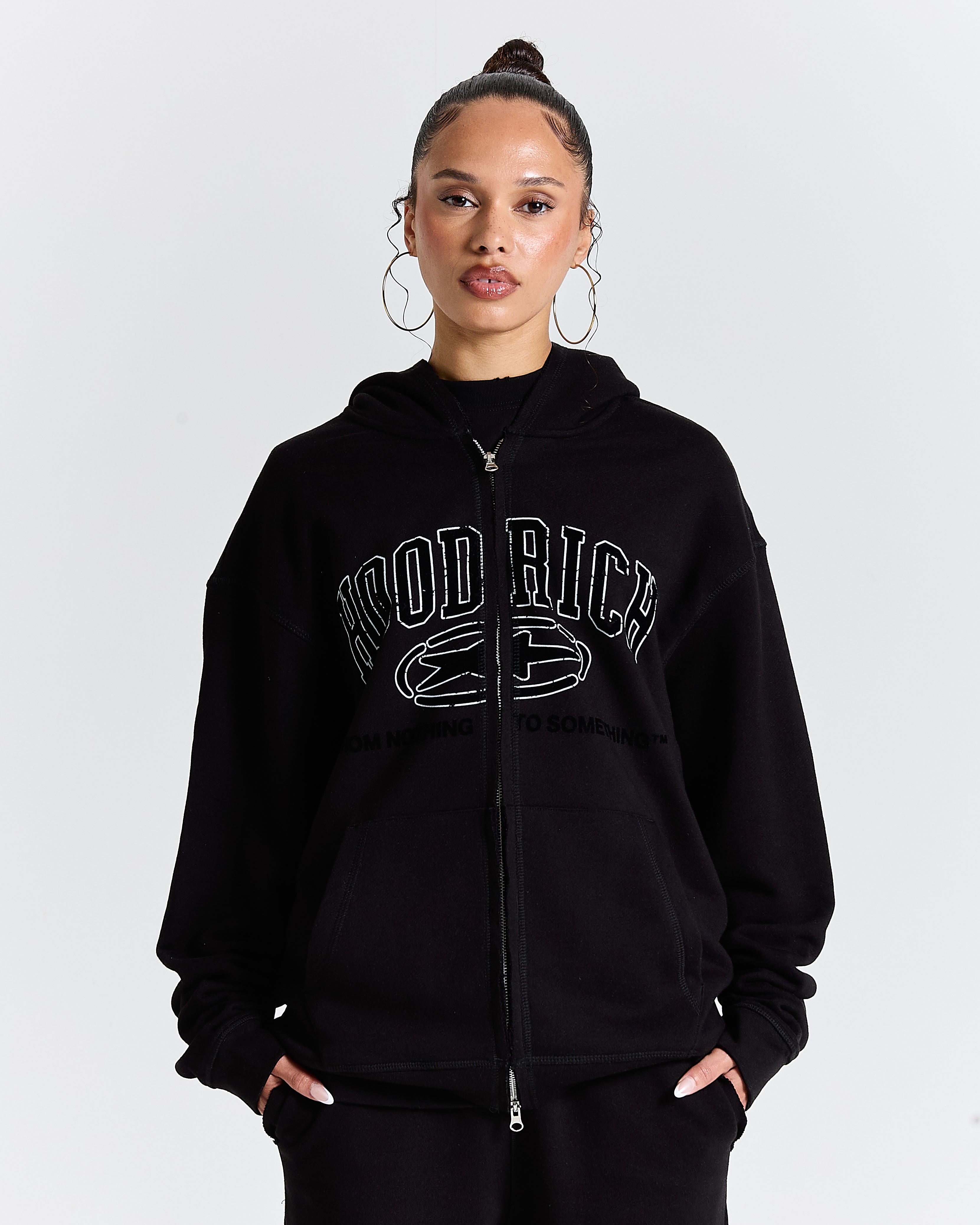 Person wearing a black hoodie with text on a plain background