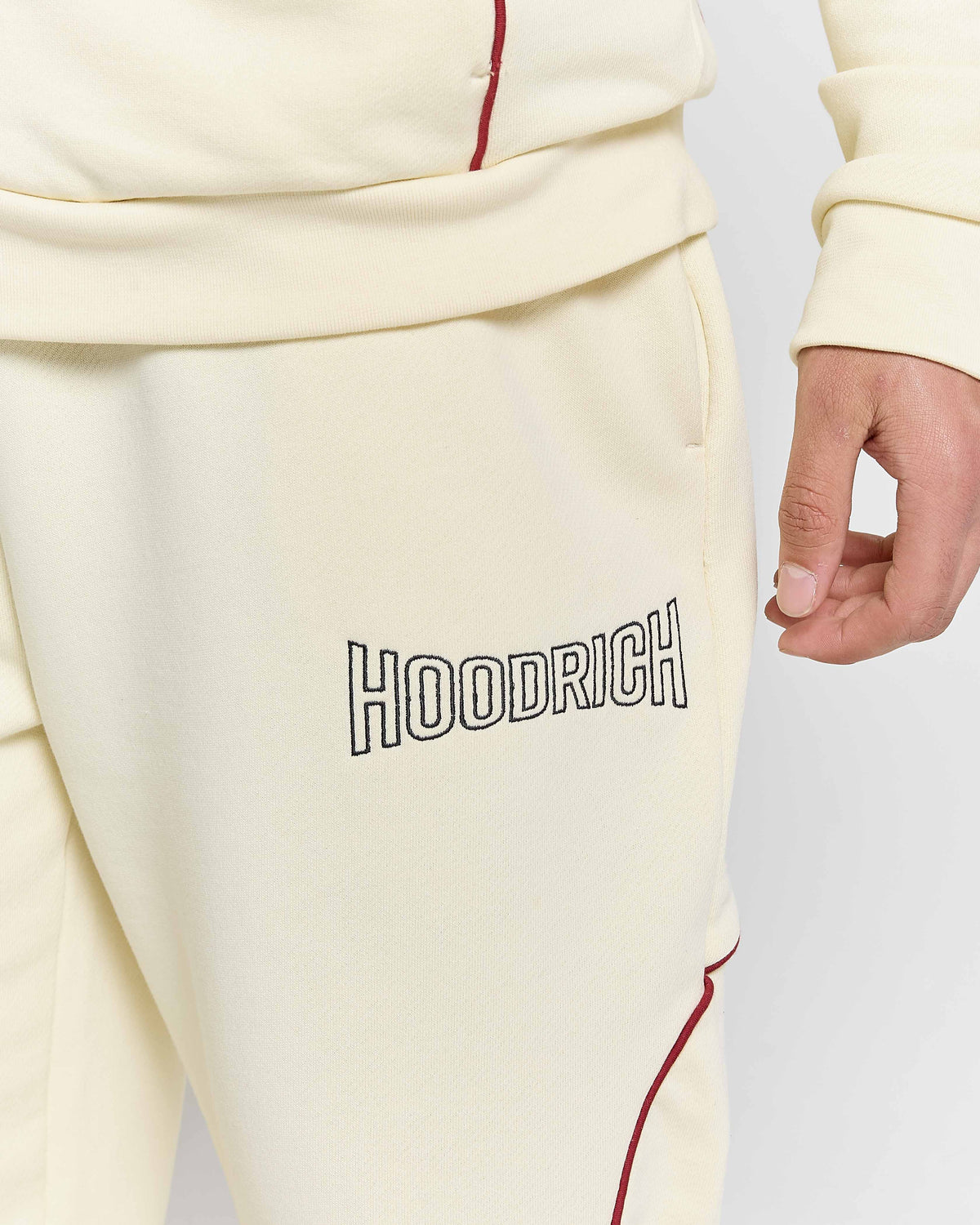 Cream-colored sweatpants with 'Hoodrich' branding on a light gray background