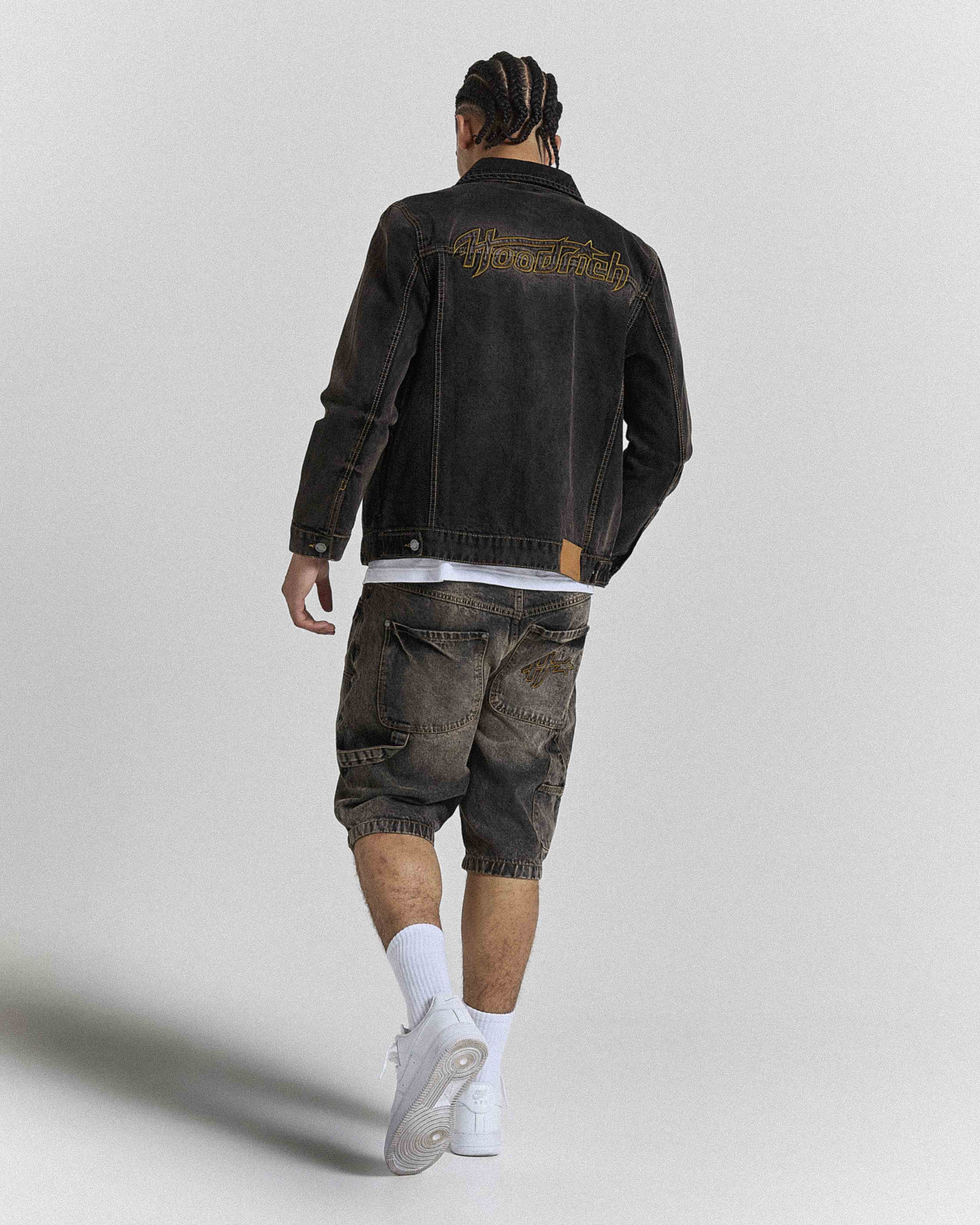 Model seen from behind wearing regular fit black rust washed denim jorts and a matching jacket.