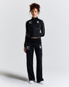 Displays a model wearing the Black 'Hoodrich' branded women's Glide Football Full Tracksuit 