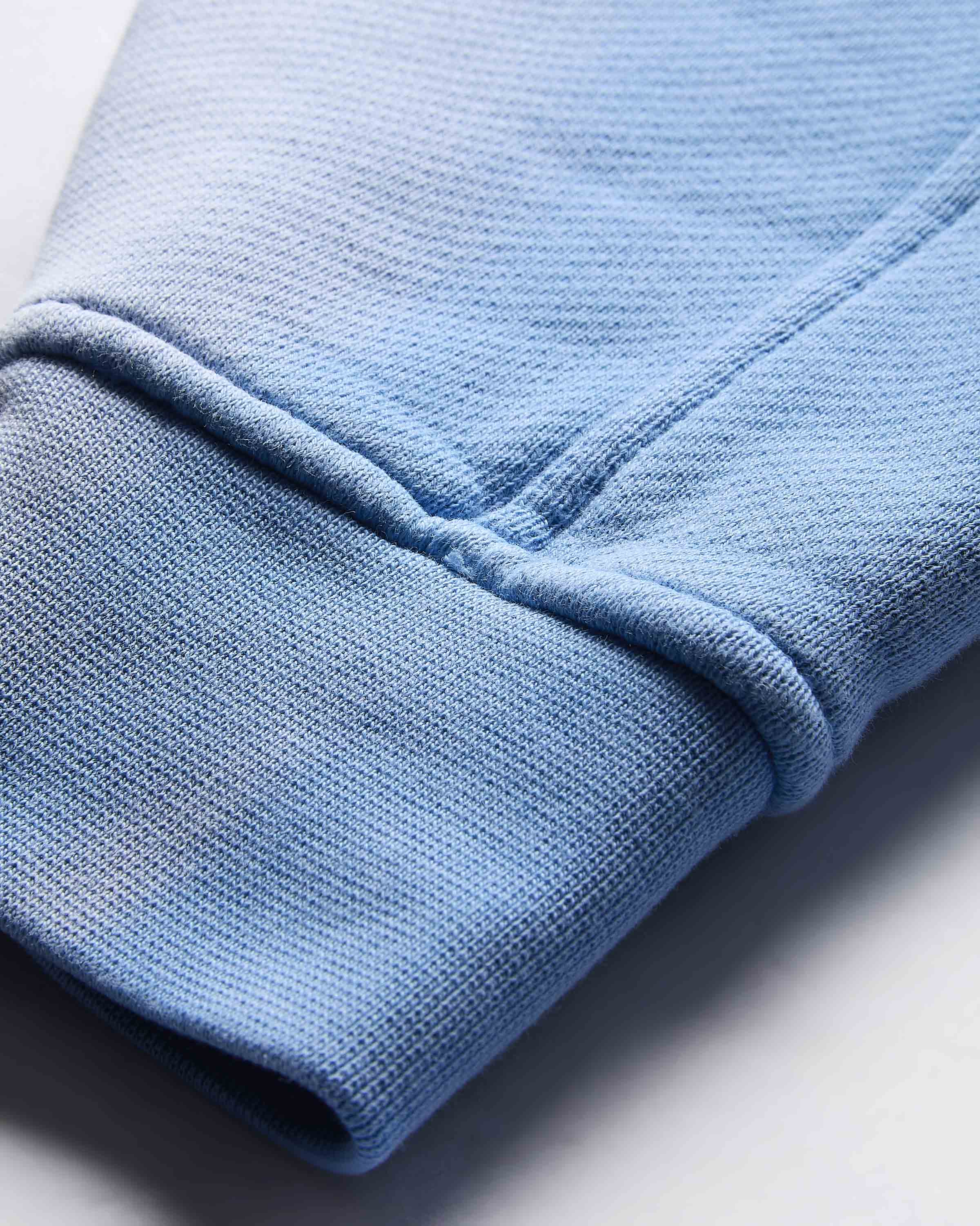 Close-up of the ribbed cuff on the sleeve of the blue cropped hoodie.