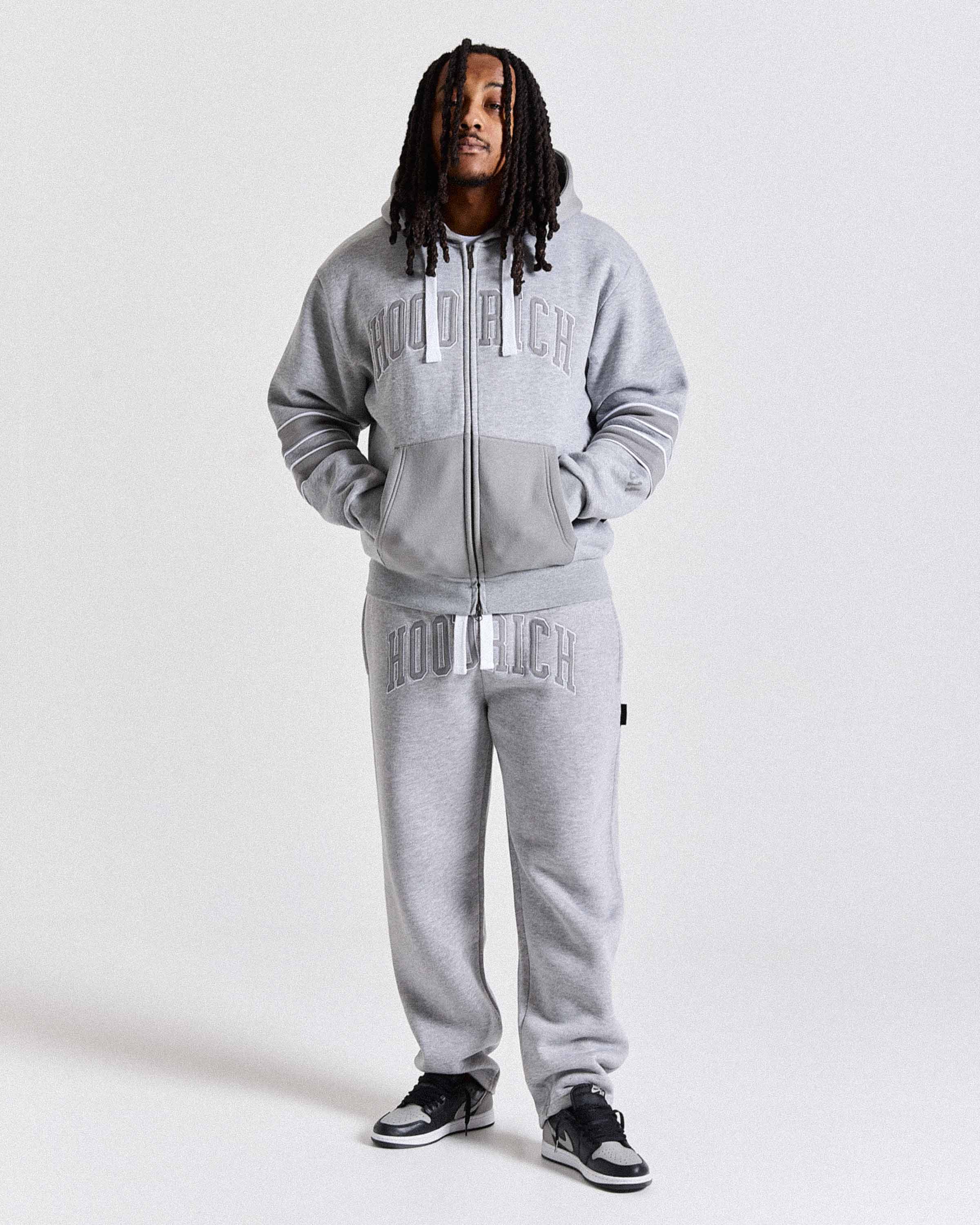 Person wearing a gray tracksuit with 'Hoodrich' branding on a white background