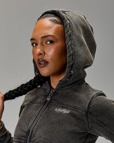 Person wearing a gray hoodie with a brand logo on a gray background