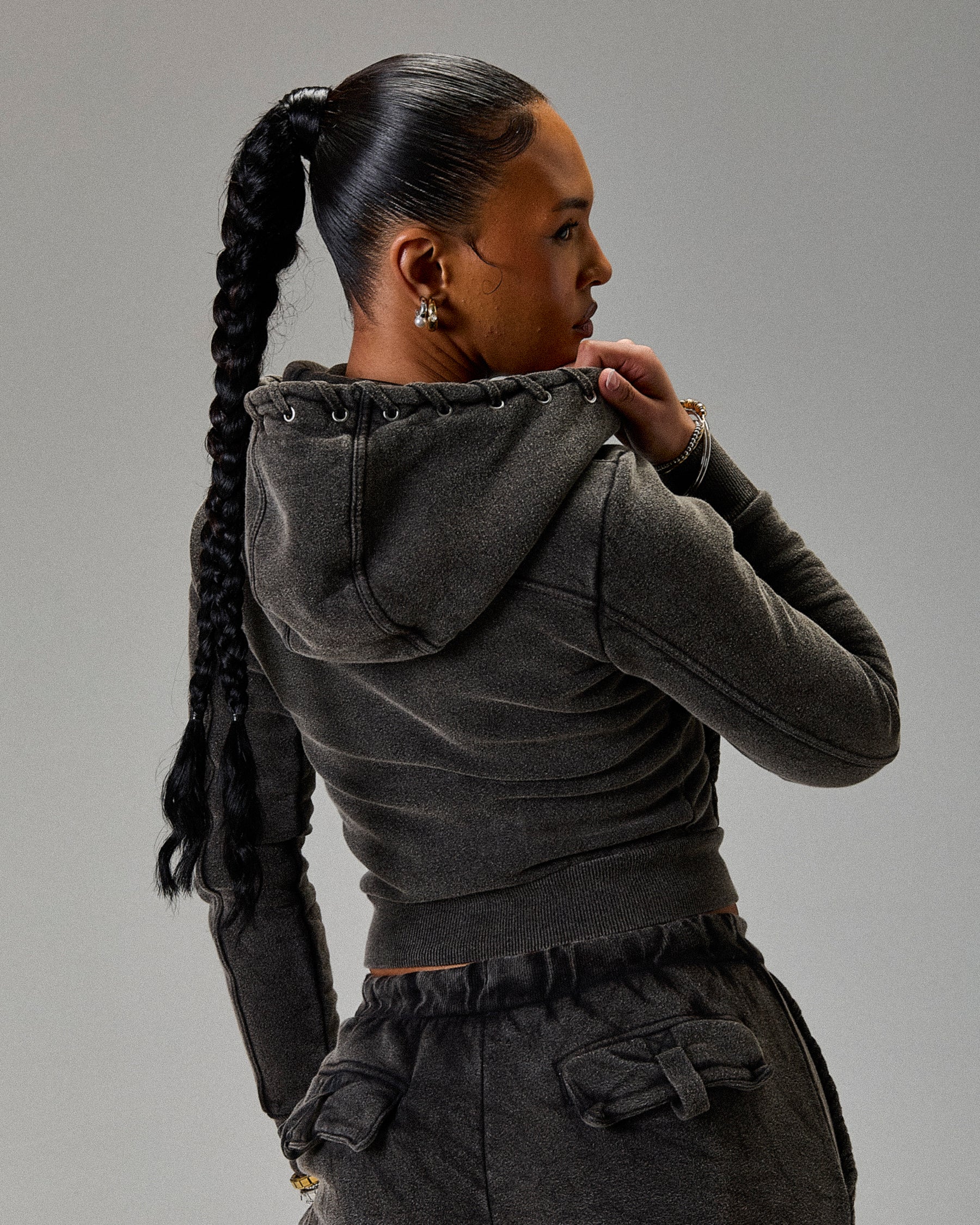 Person wearing a dark gray hoodie and pants against a plain background