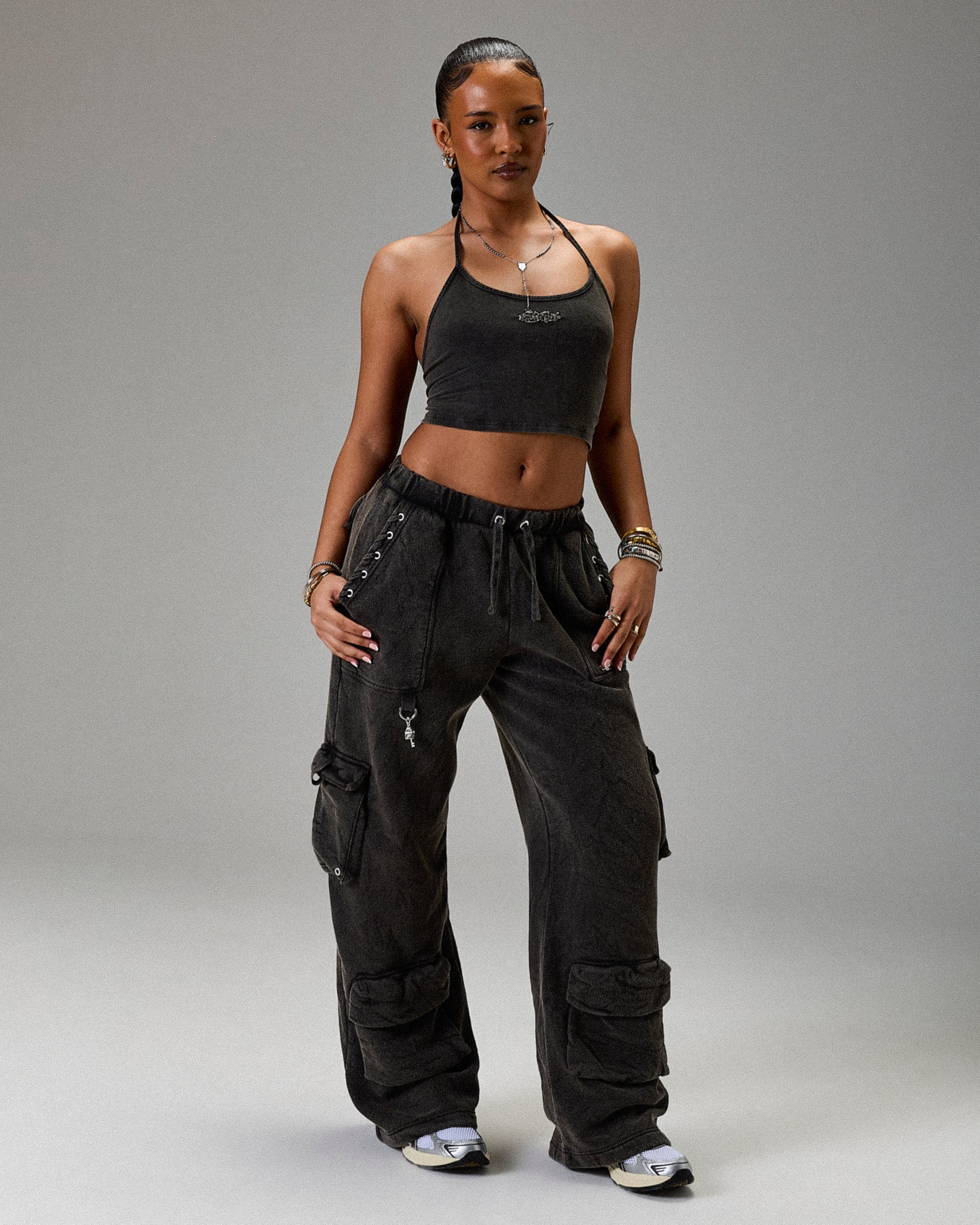 Woman wearing a black crop top and cargo pants on a gray background
