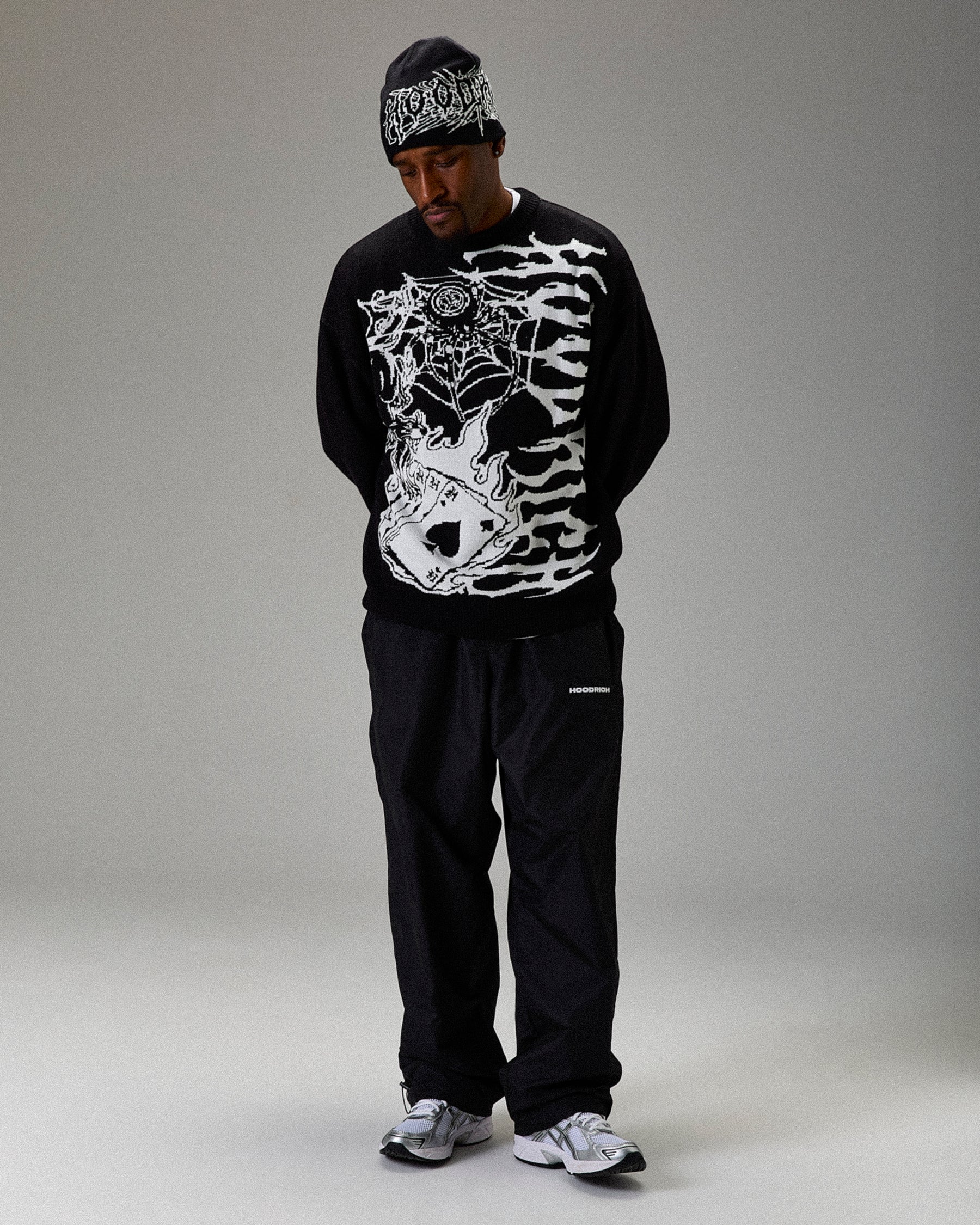 Person wearing a black sweater with white graphic design on a gray background