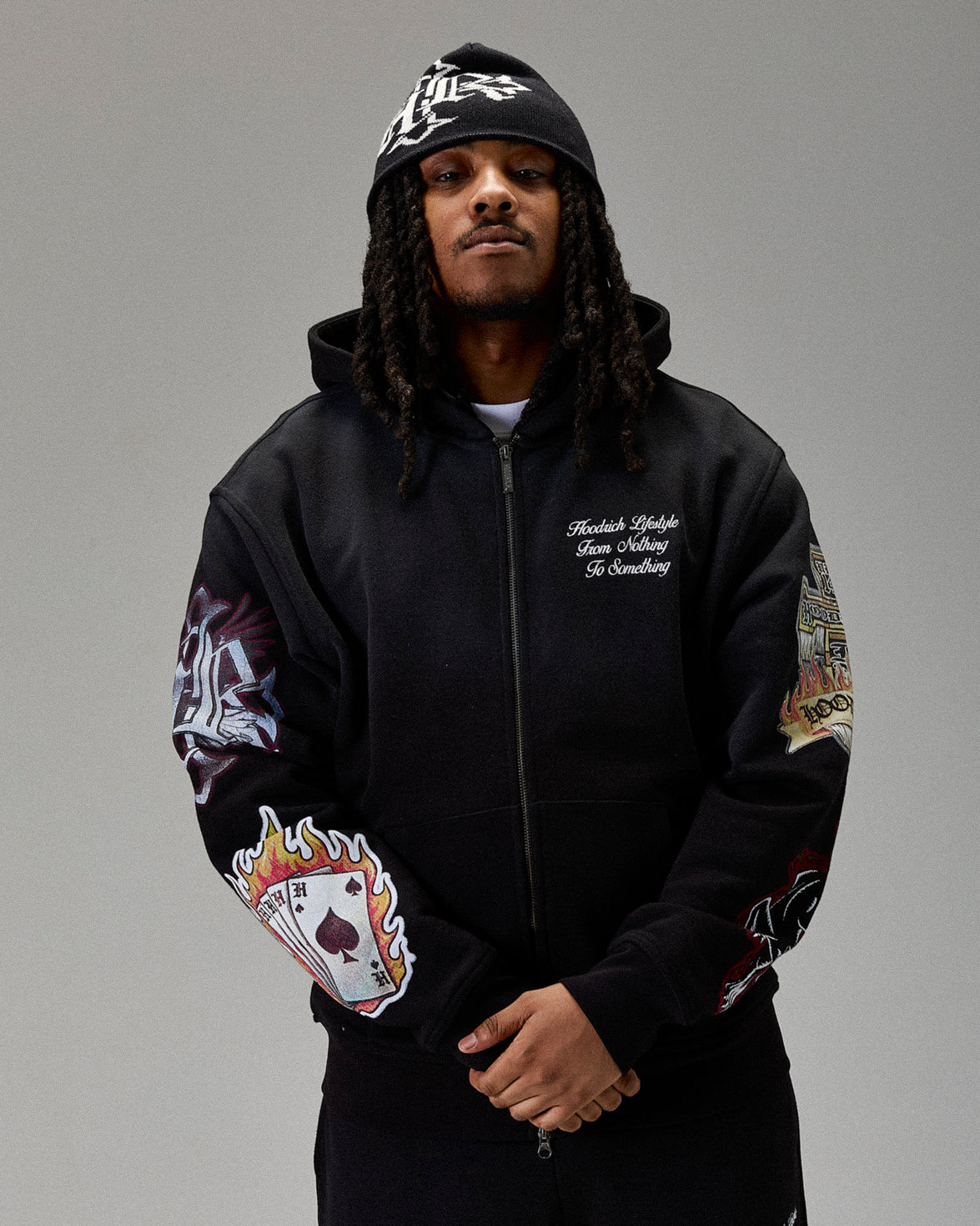 Person wearing a black zip hoodie with colorful designs on sleeves against a gray background