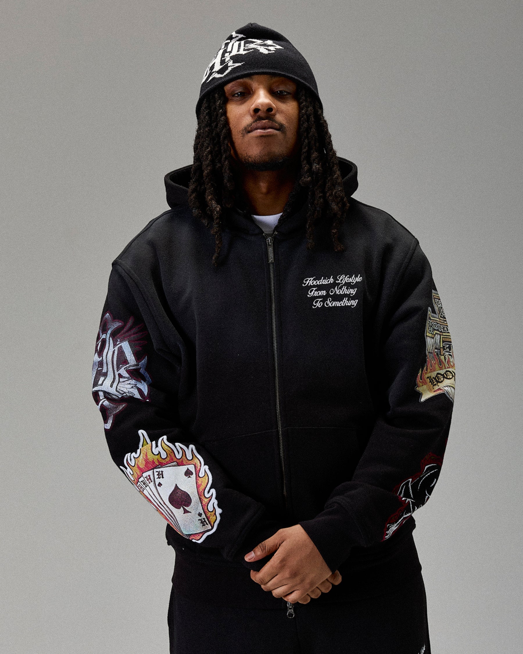 Person wearing a black zip hoodie with colorful designs on sleeves against a gray background