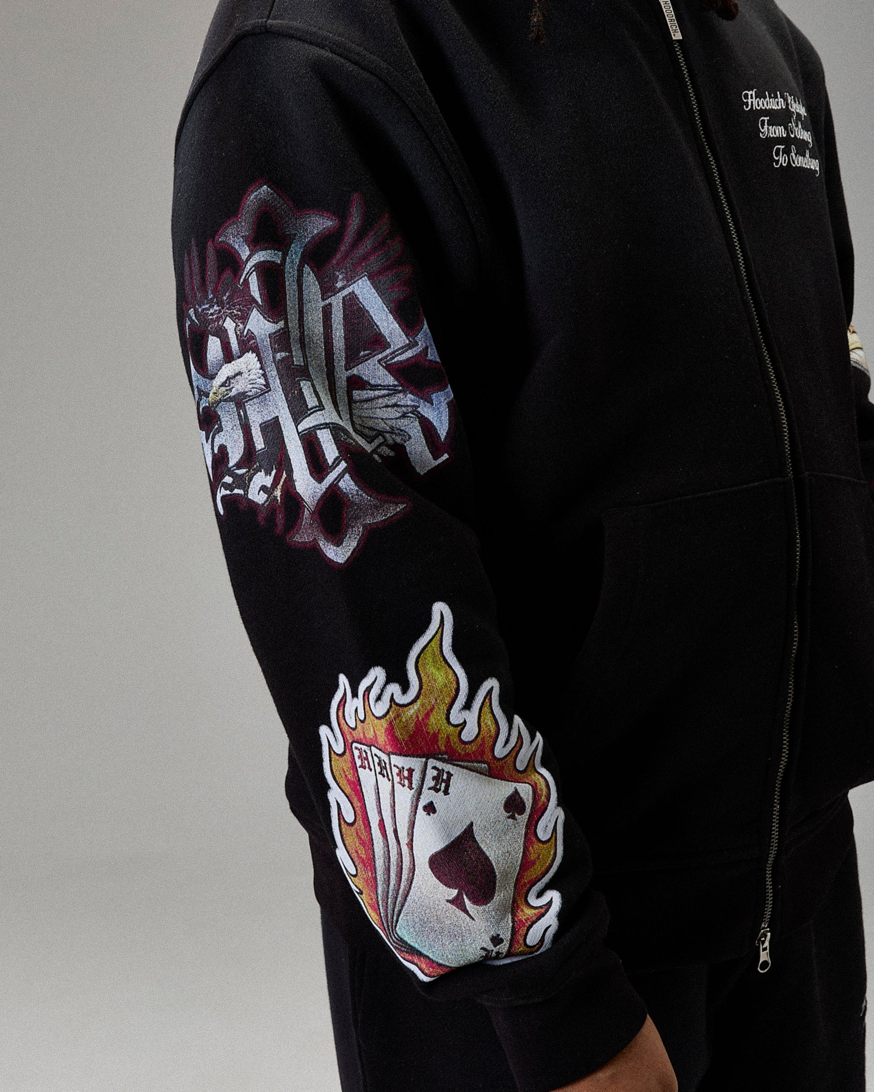 Black hoodie with colorful graphic designs on sleeves against a neutral background