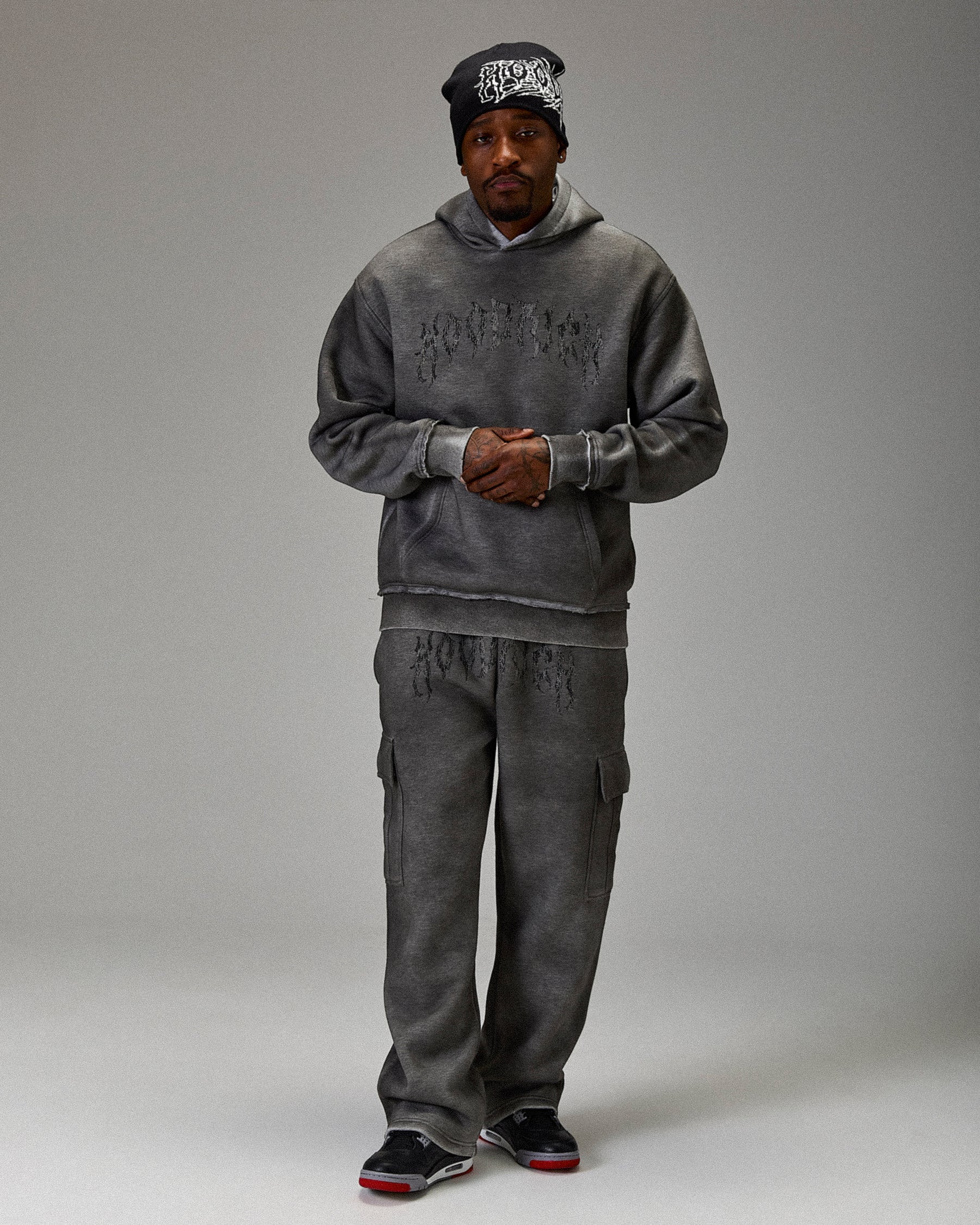 Person wearing a gray hoodie and pants set on a plain background