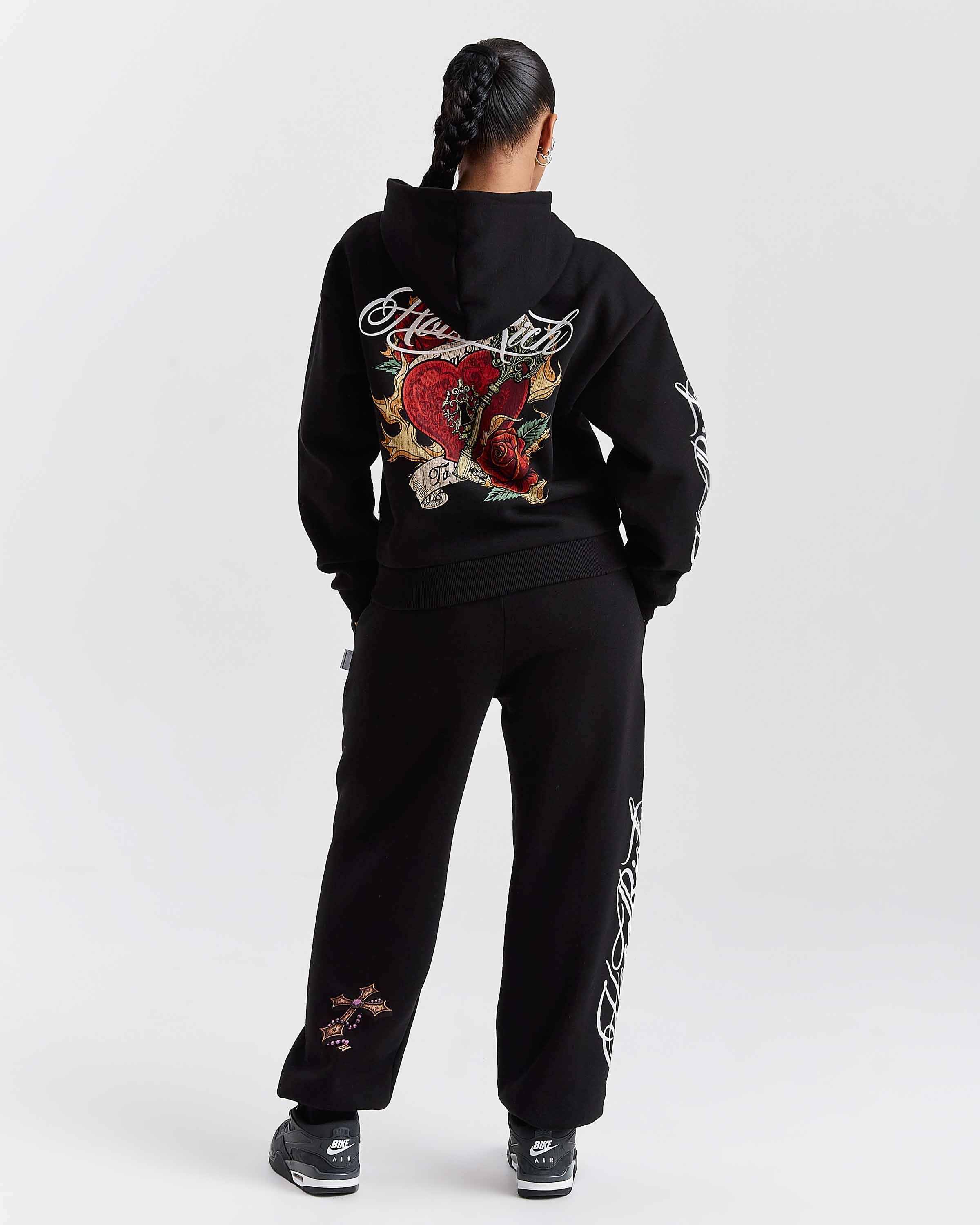 Person wearing a black tracksuit with floral designs on a white background