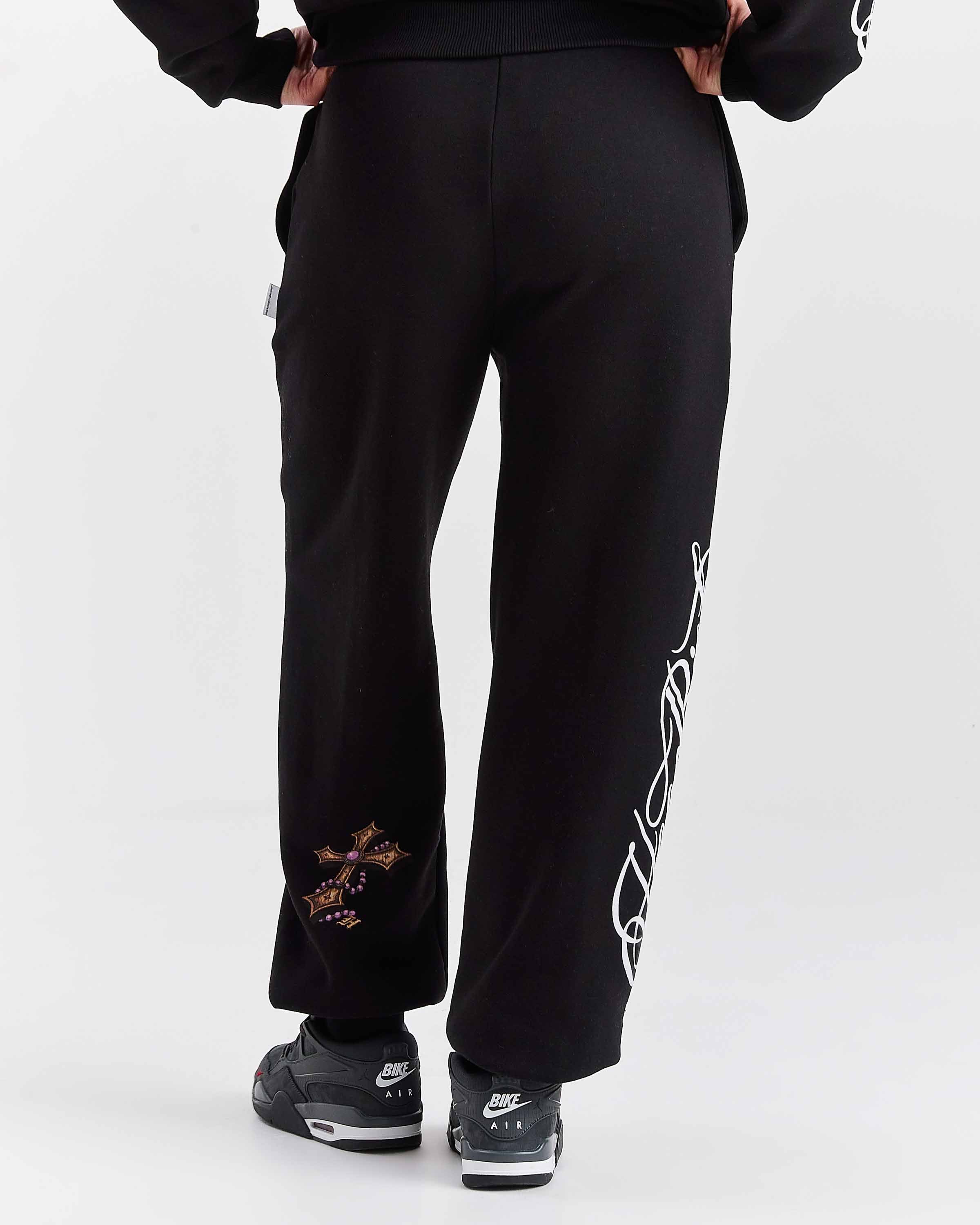 Black pants with white text design worn by a person on a white background