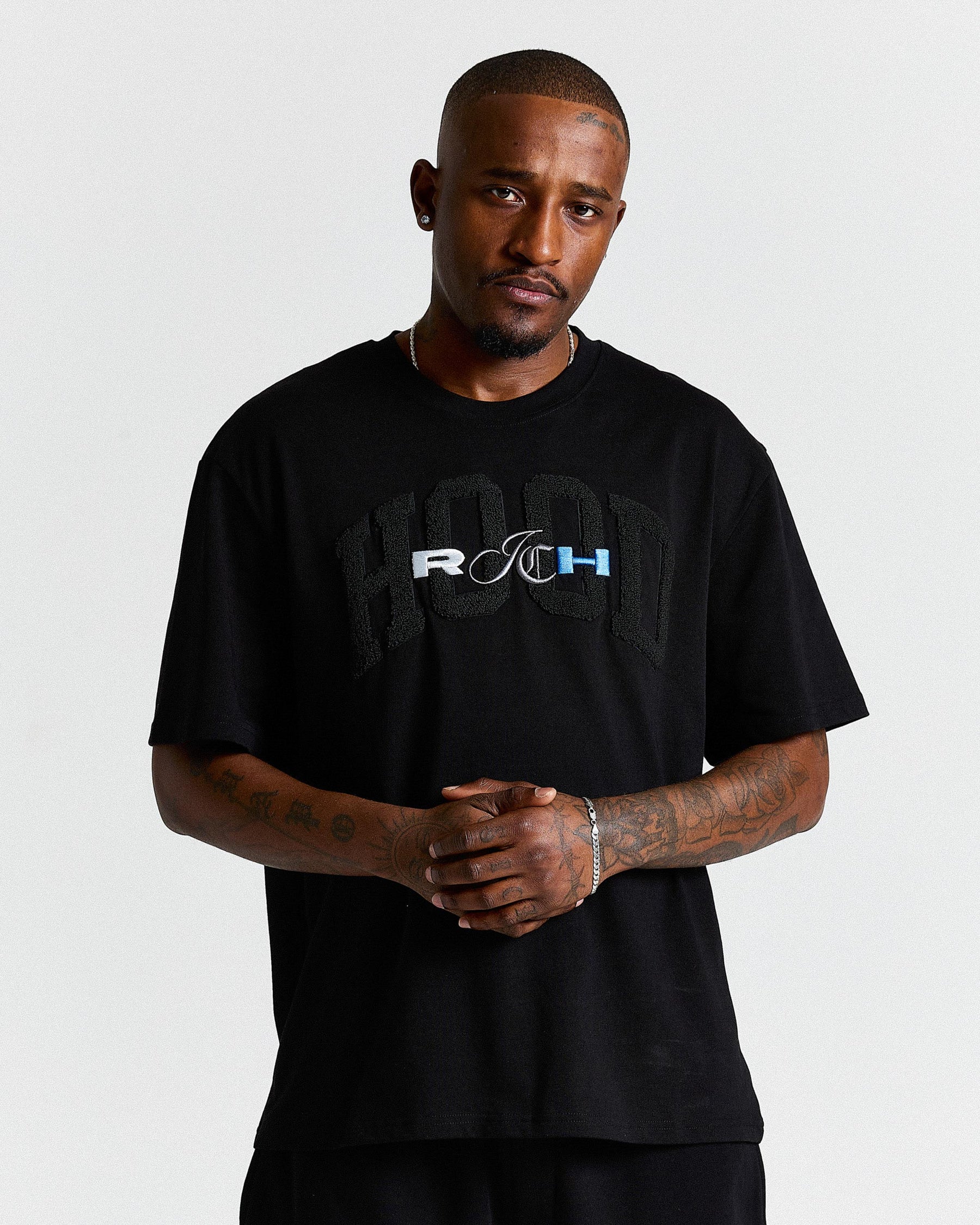 Man wearing a black t-shirt with a logo on a plain background