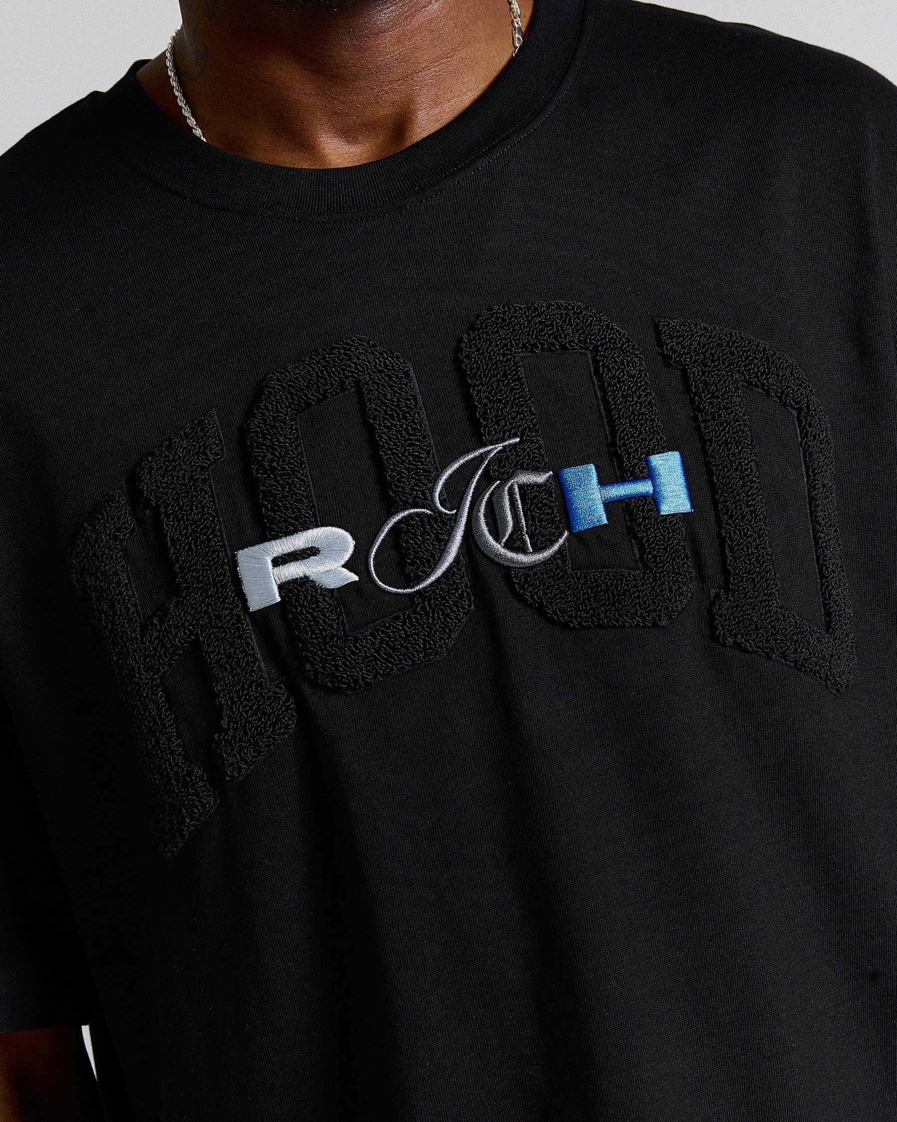 Black sweatshirt with embroidered text on a person wearing it.