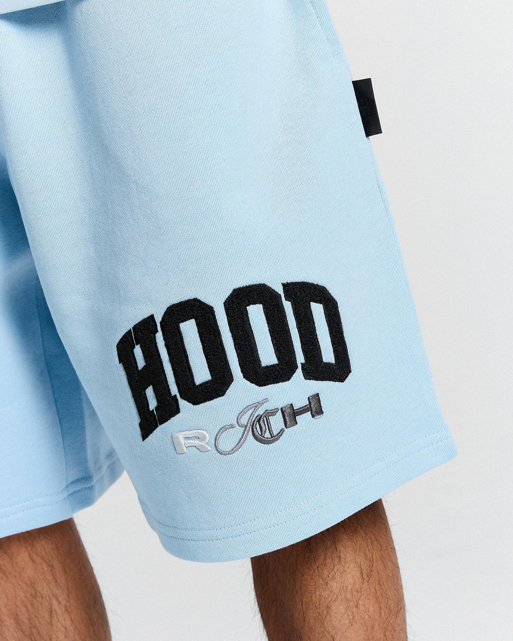 Light blue shorts with black 'Hoodrich' logo on a neutral background