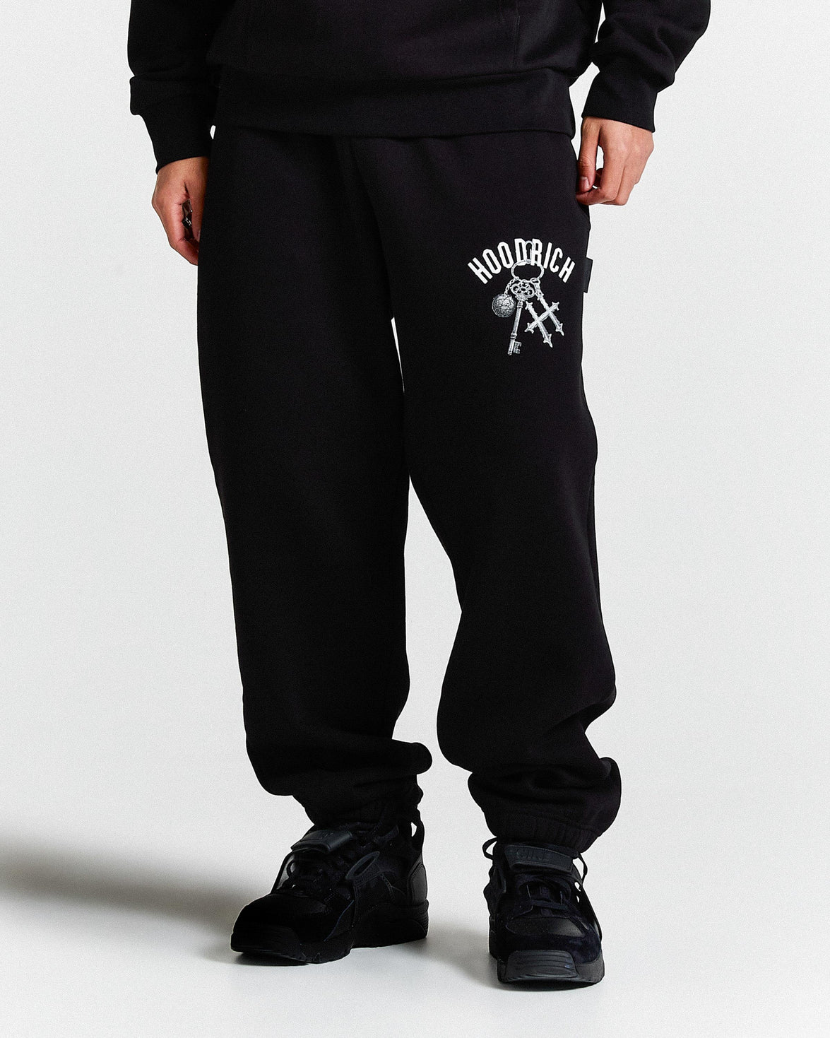 Person wearing black sweatpants with a logo on a white background