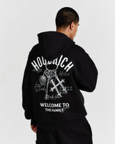 Person wearing a black hoodie with white text and graphics on the back, standing against a light gray background.