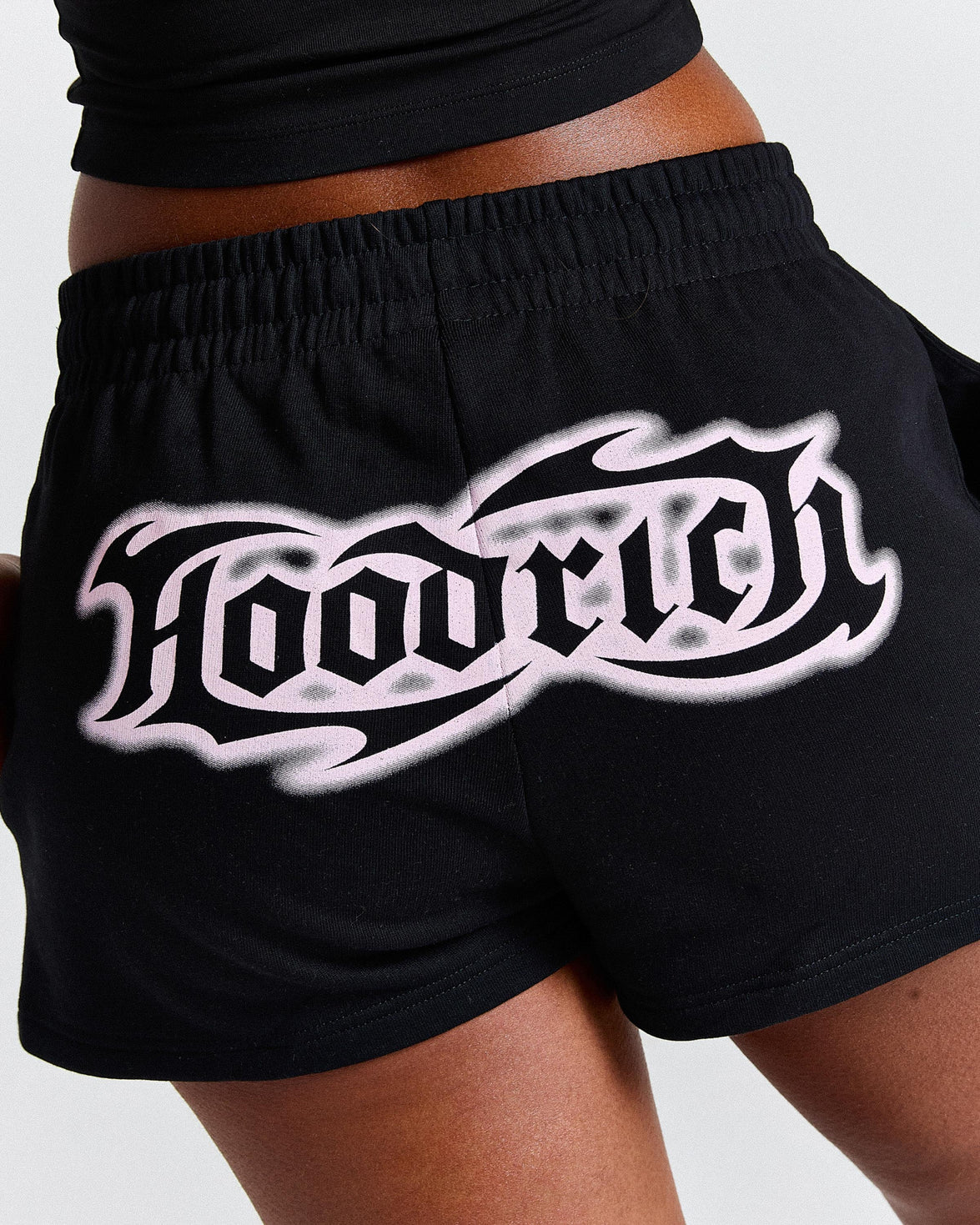 Black shorts with a white logo on a neutral background