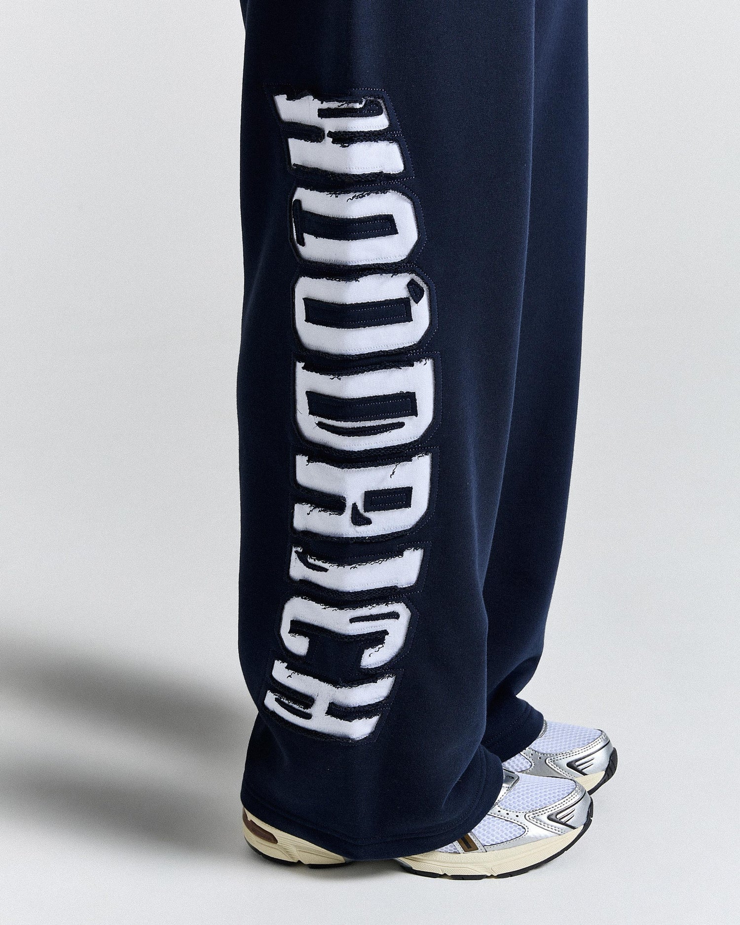 Navy blue sweatpants with white text on a light gray background
