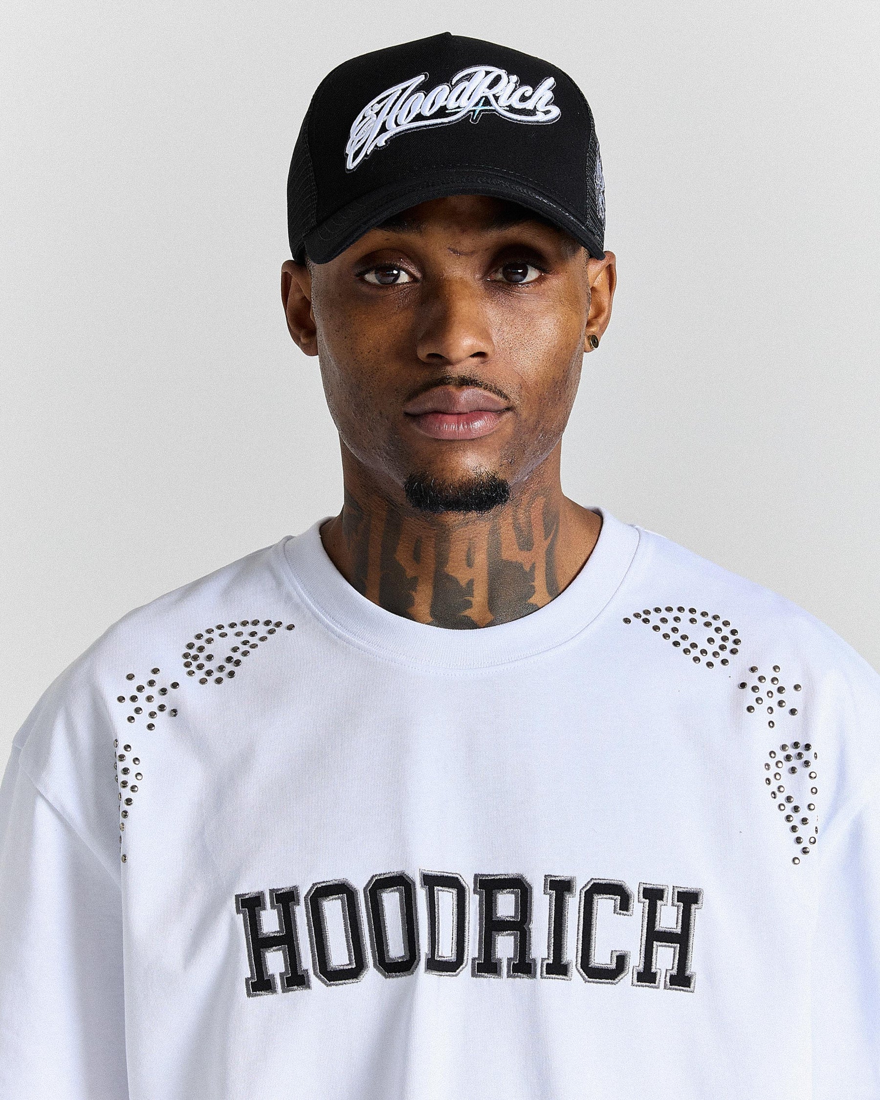 Person wearing a black 'Hoodrich' cap and white shirt with 'Hoodrich' text on a plain background