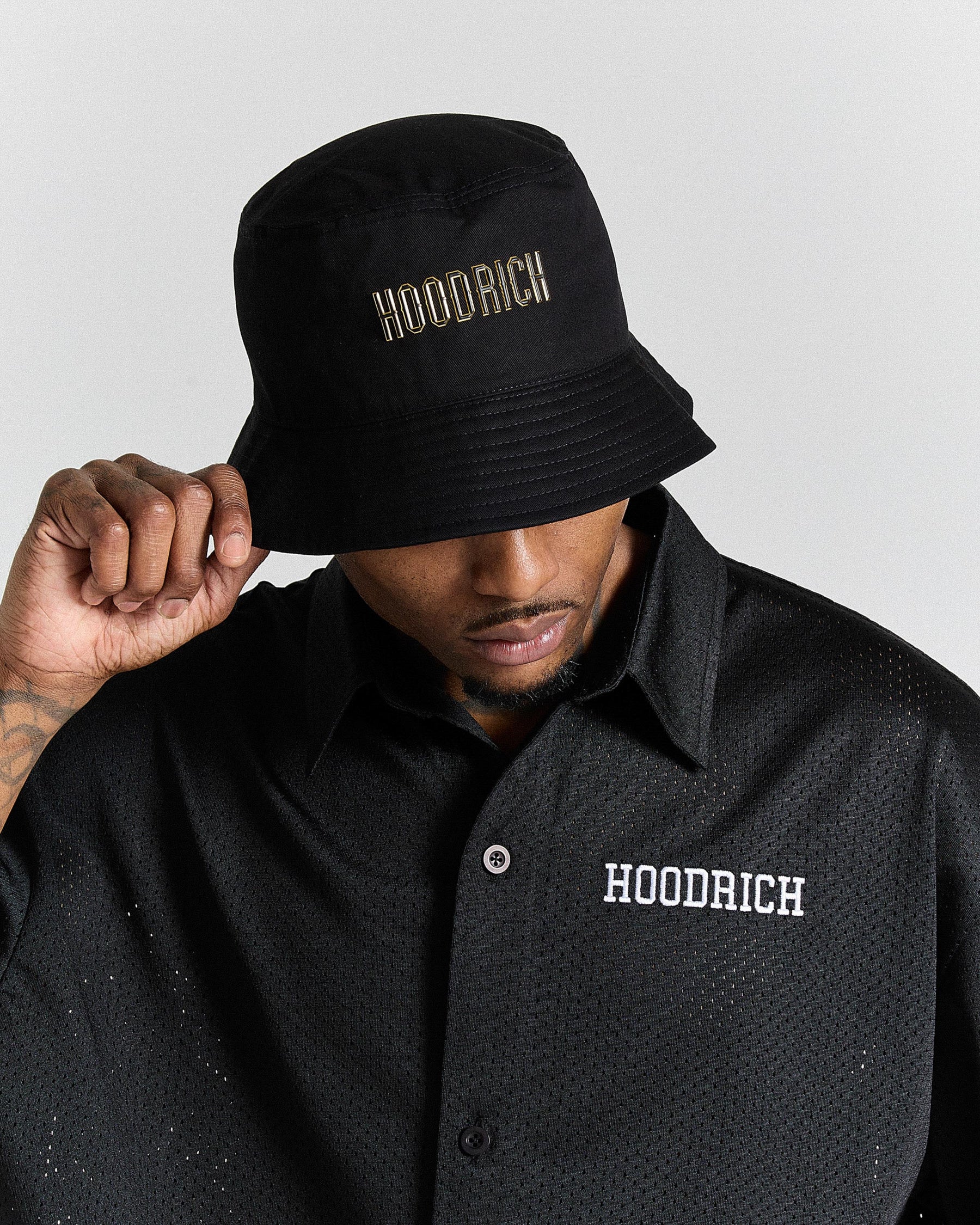Person wearing a black bucket hat and black shirt with 'Hoodrich' branding.