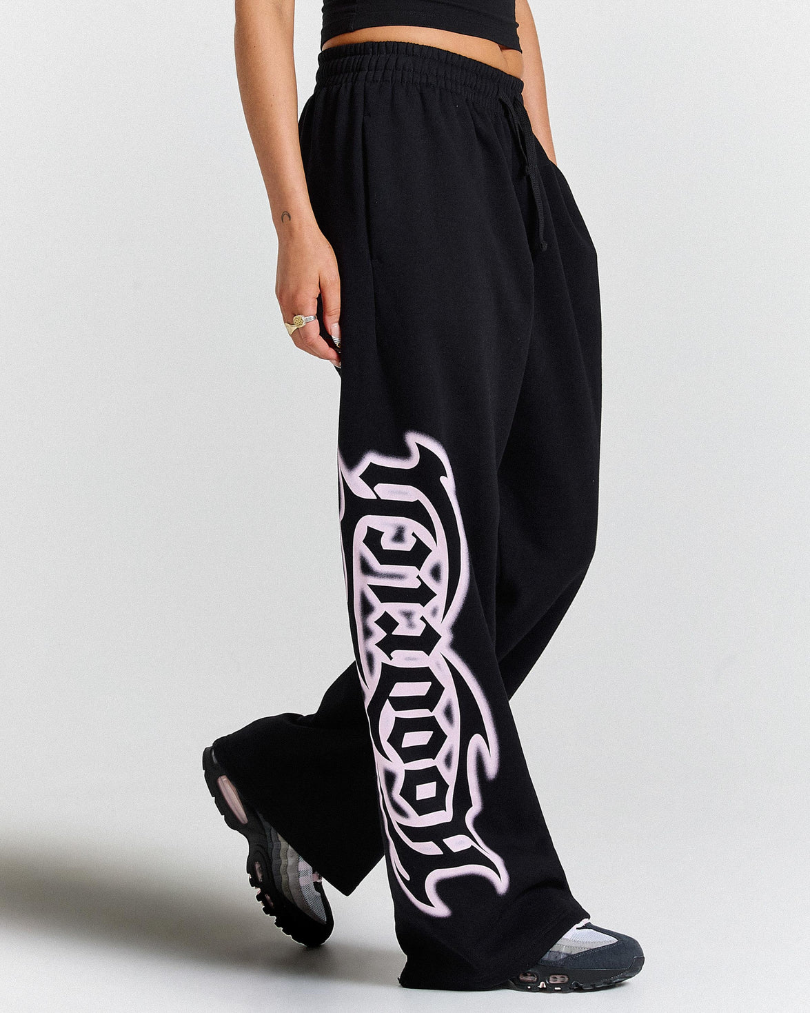 Black pants with white graphic design worn by a person on a light gray background